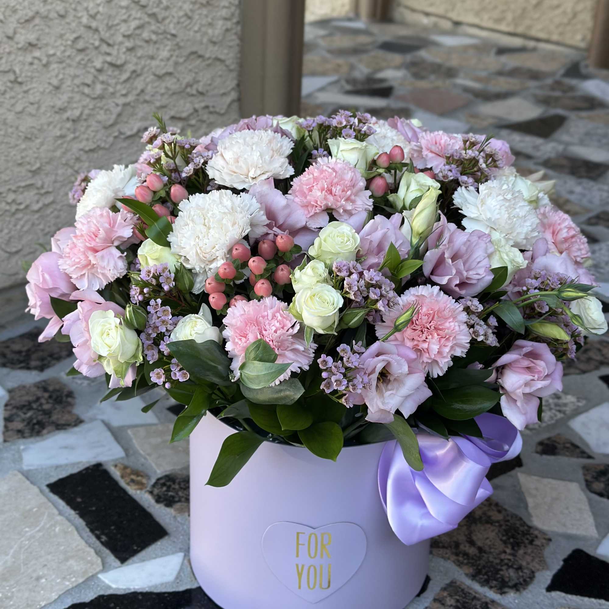 Pastel pink and white flower arrangement in a lavender hat box with a ribbon