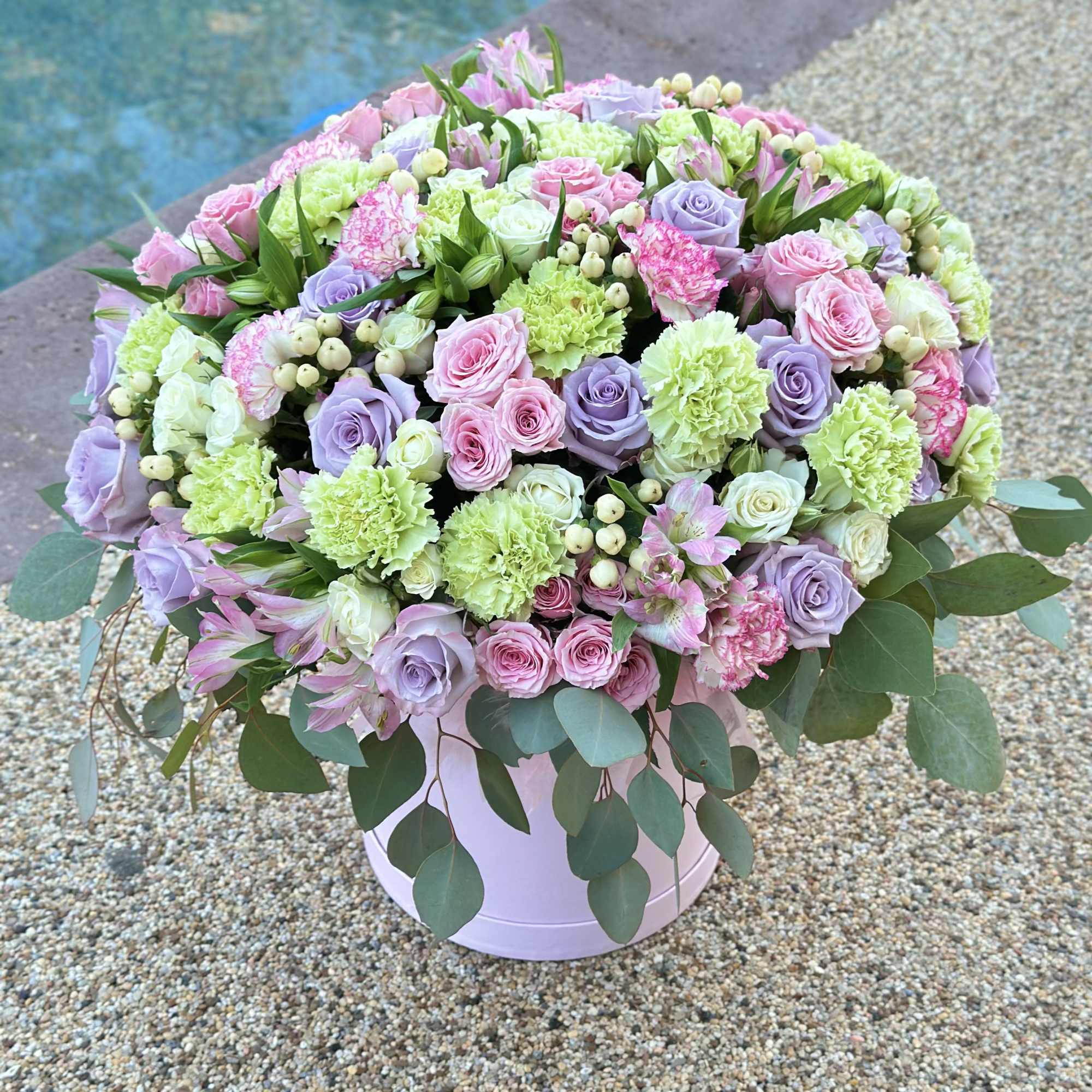 Large pastel bouquet of roses, carnations, and alstroemeria in a round box