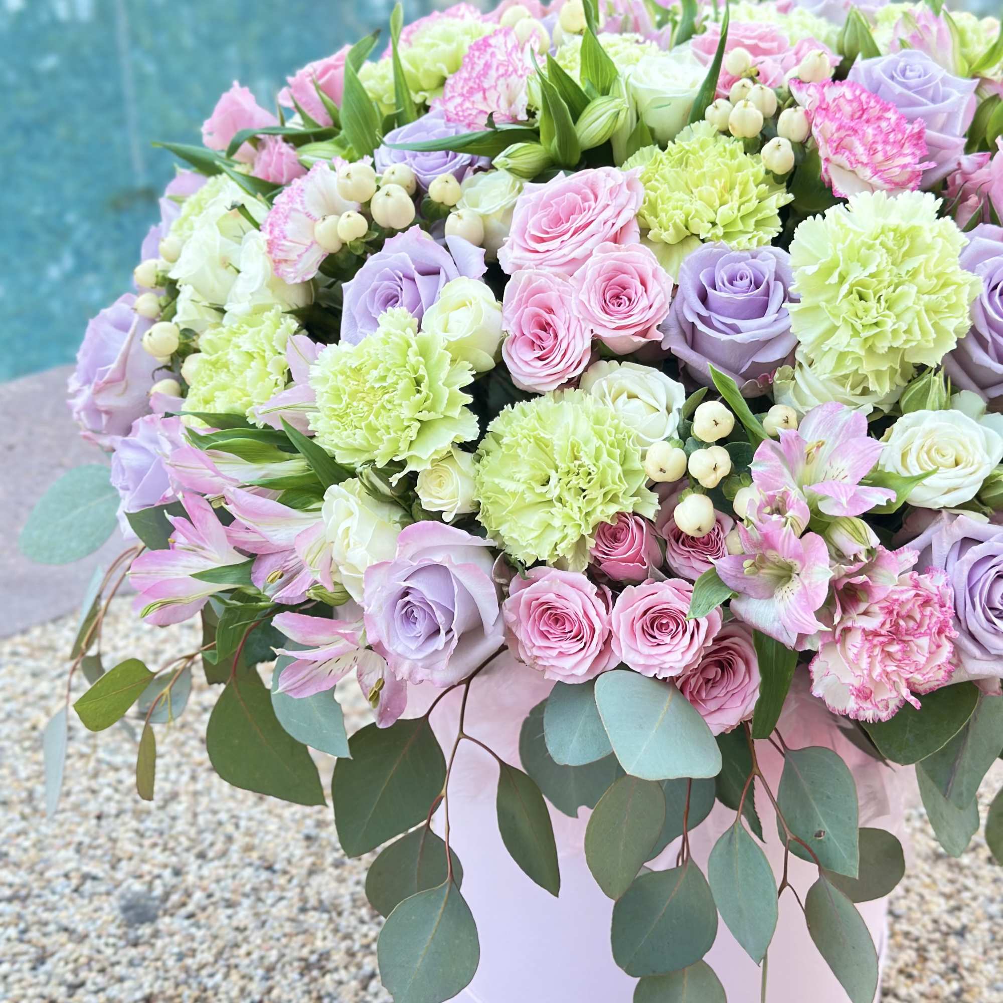 Pastel bouquet of roses, carnations, and alstroemeria in a pink hatbox
