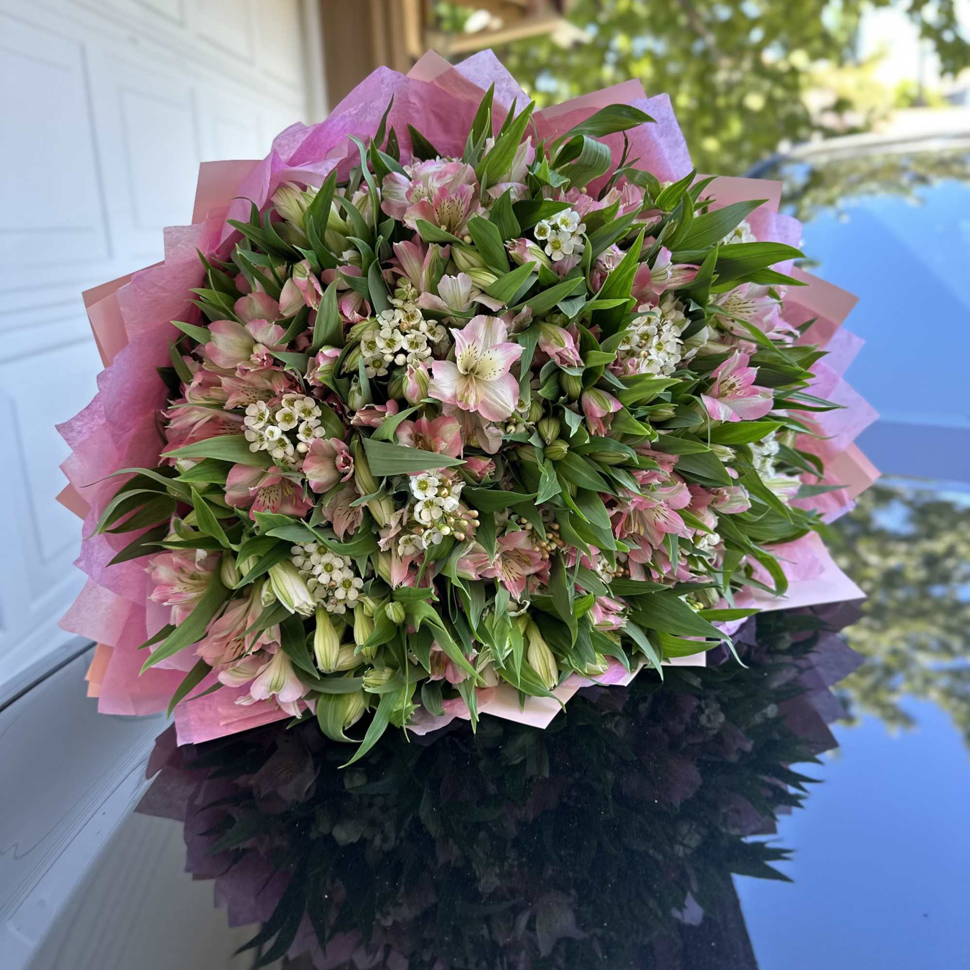 Large bouquet of pink and white flowers wrapped in pink paper