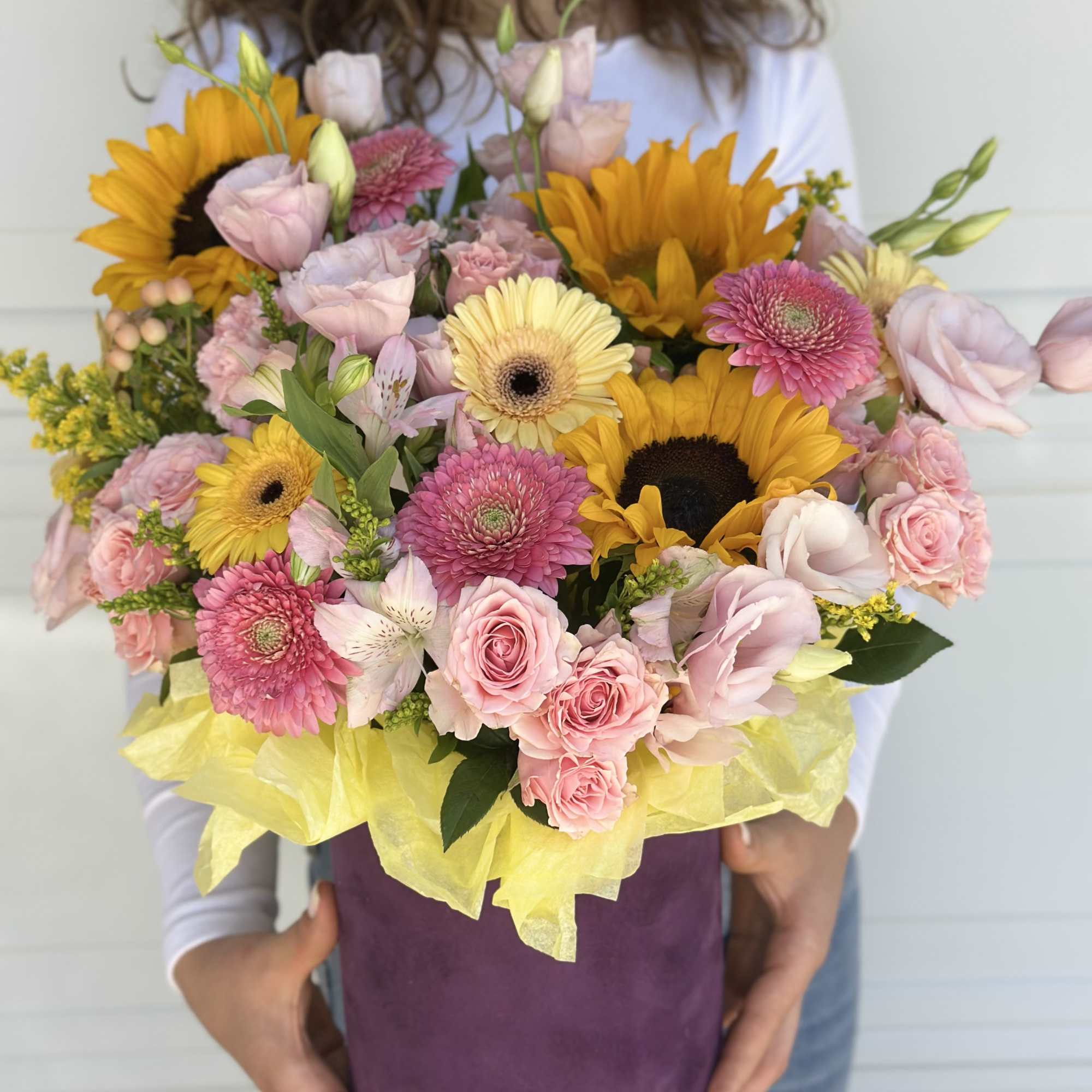 Mixed bouquet of sunflowers, pink roses, and gerbera daisies in a purple box