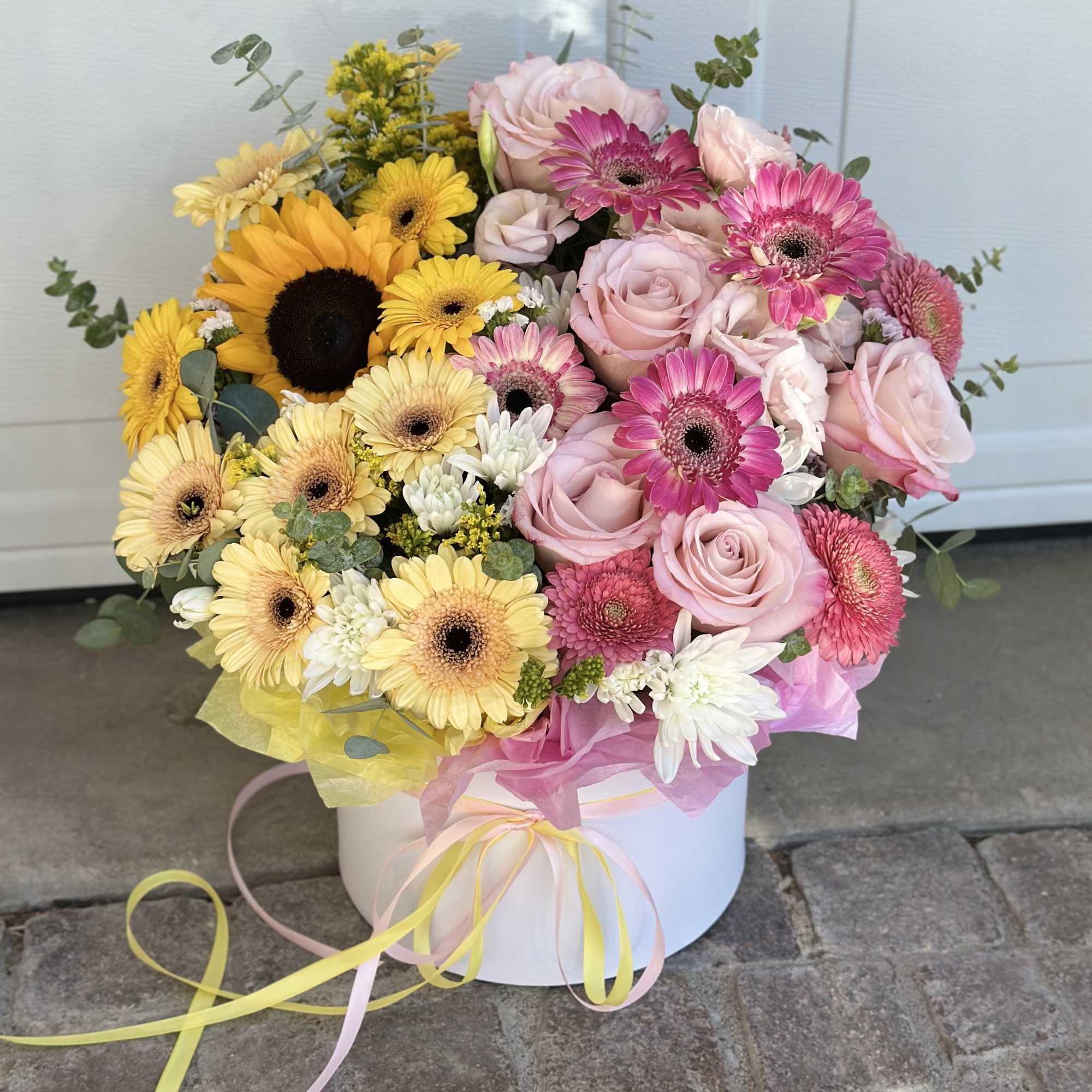 Mixed bouquet of pink roses, gerbera daisies, and sunflowers in a white box