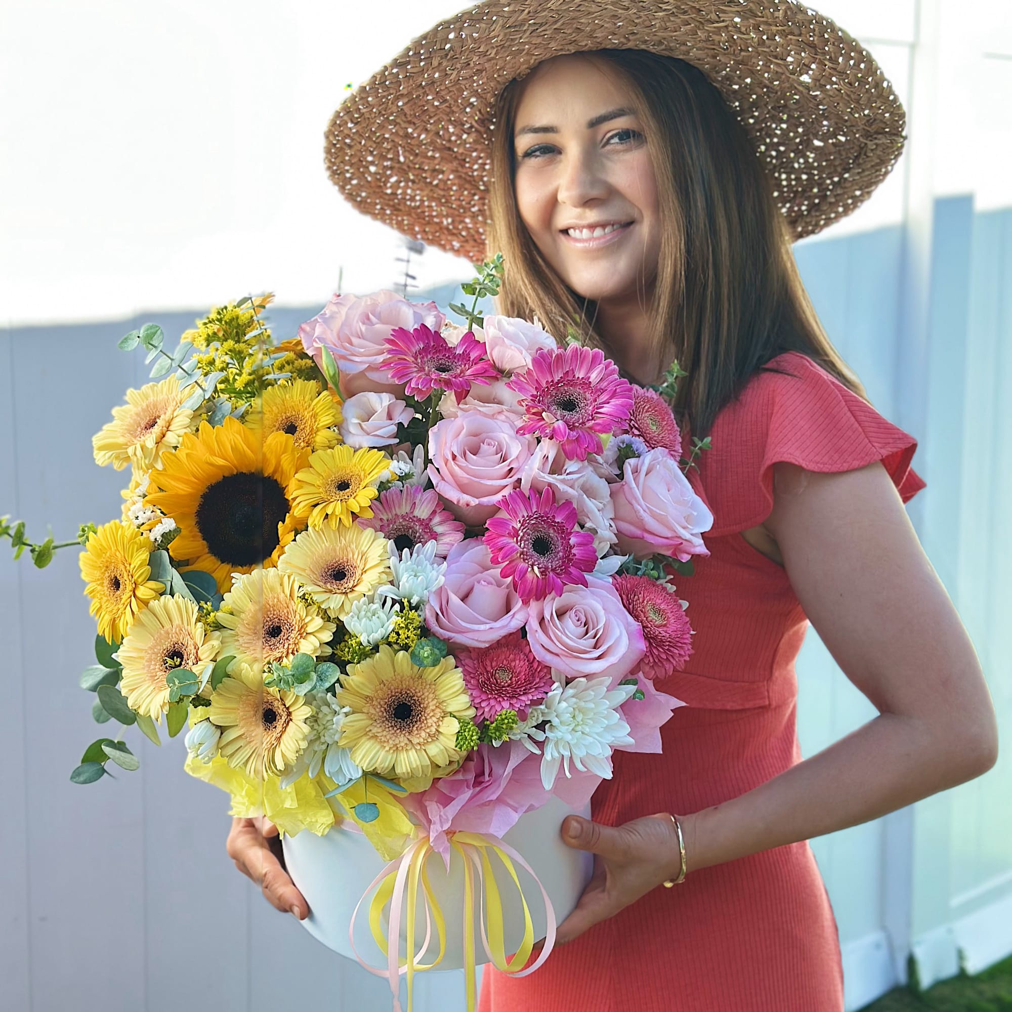 Woman holding a large pastel flower arrangement in a white hatbox