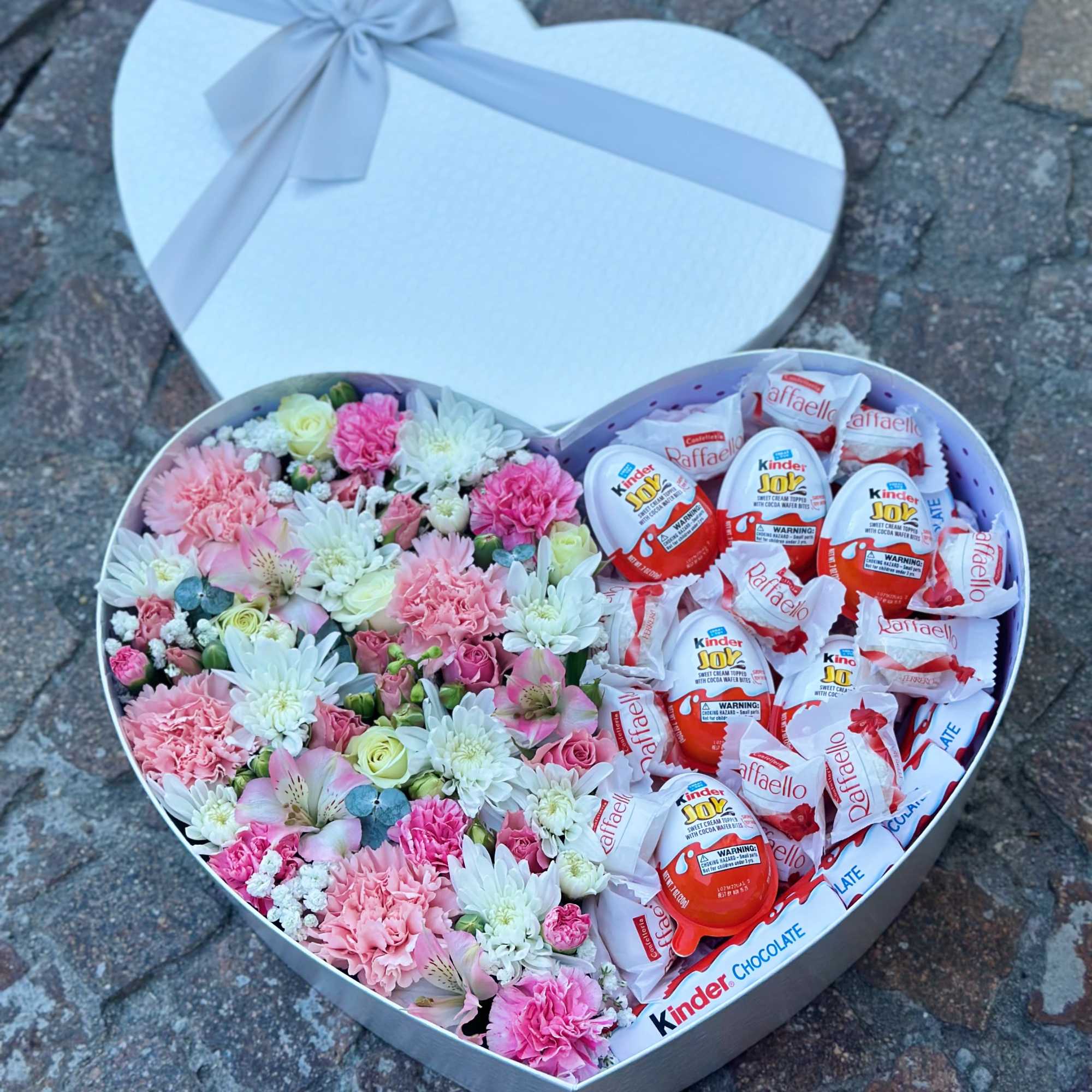 Heart-shaped gift box with pink and white flowers and chocolates