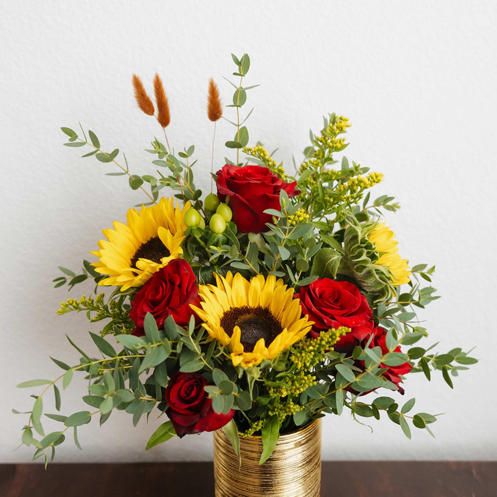 Red roses and sunflowers in a gold vase