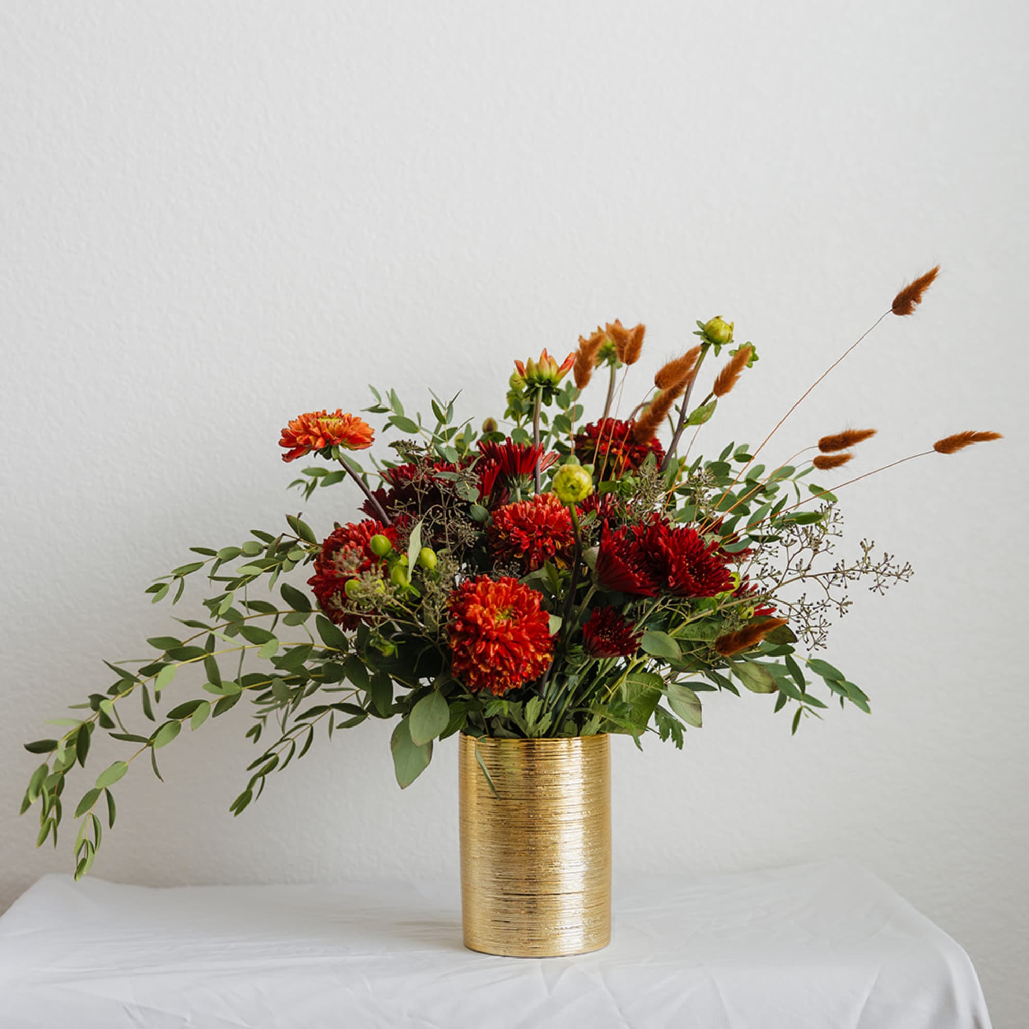 Red and orange flowers arranged in a gold vase