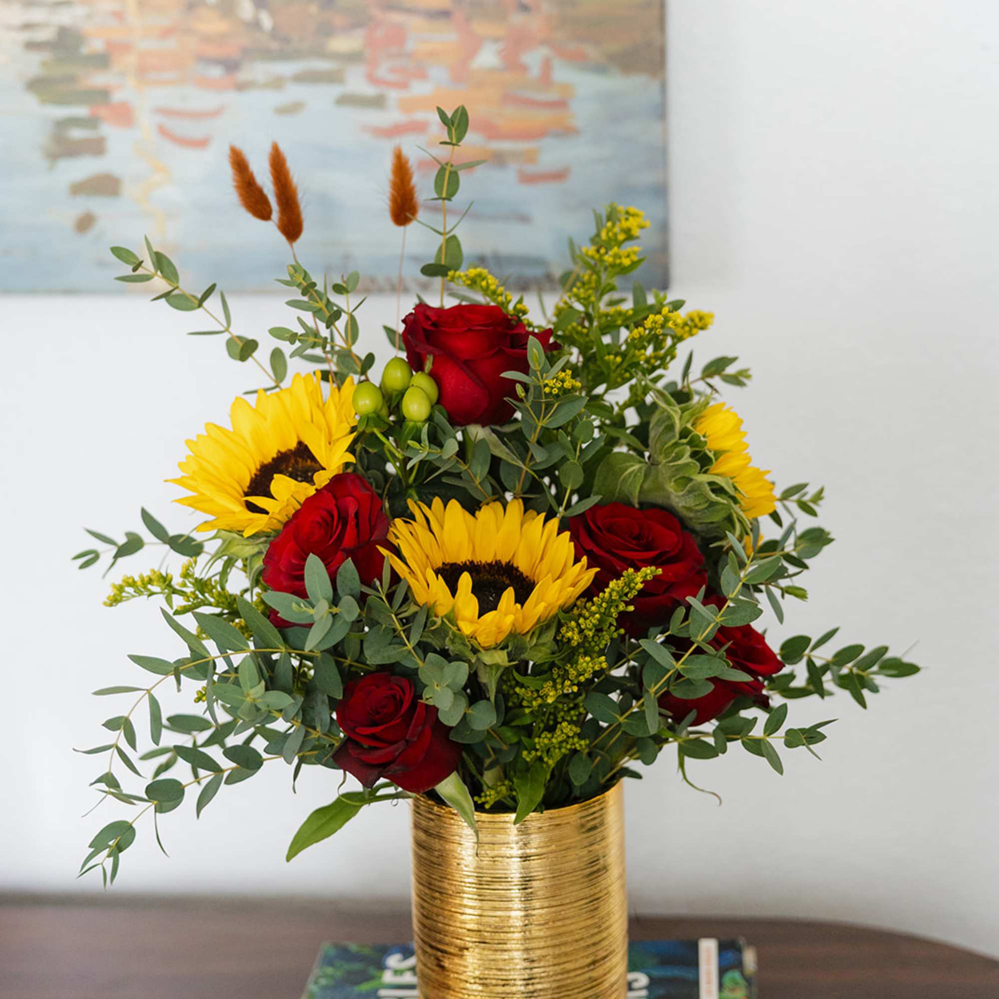 Red roses and sunflowers arranged in a gold vase