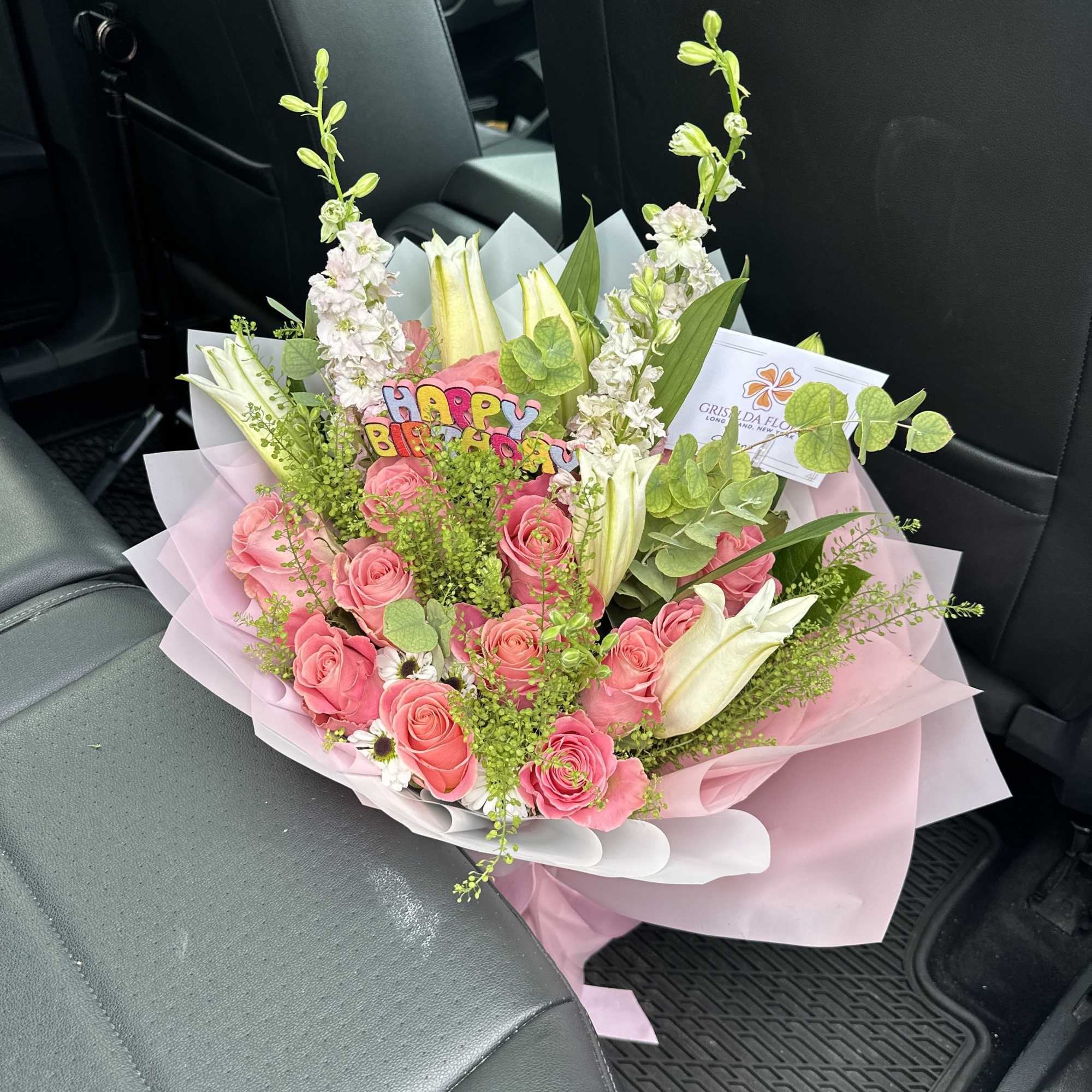 Pink rose bouquet with white lilies and a birthday sign in pink wrapping