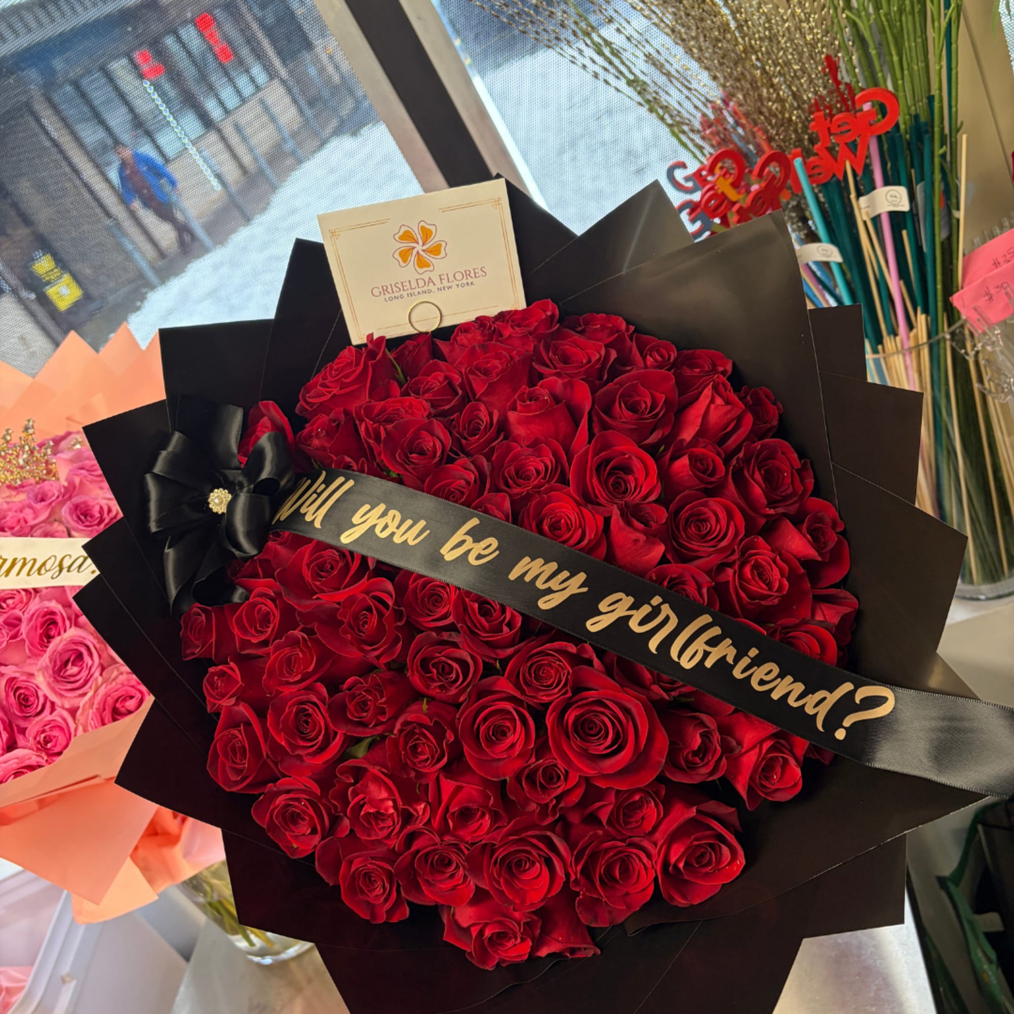 Large bouquet of red roses wrapped in black paper with a ribbon