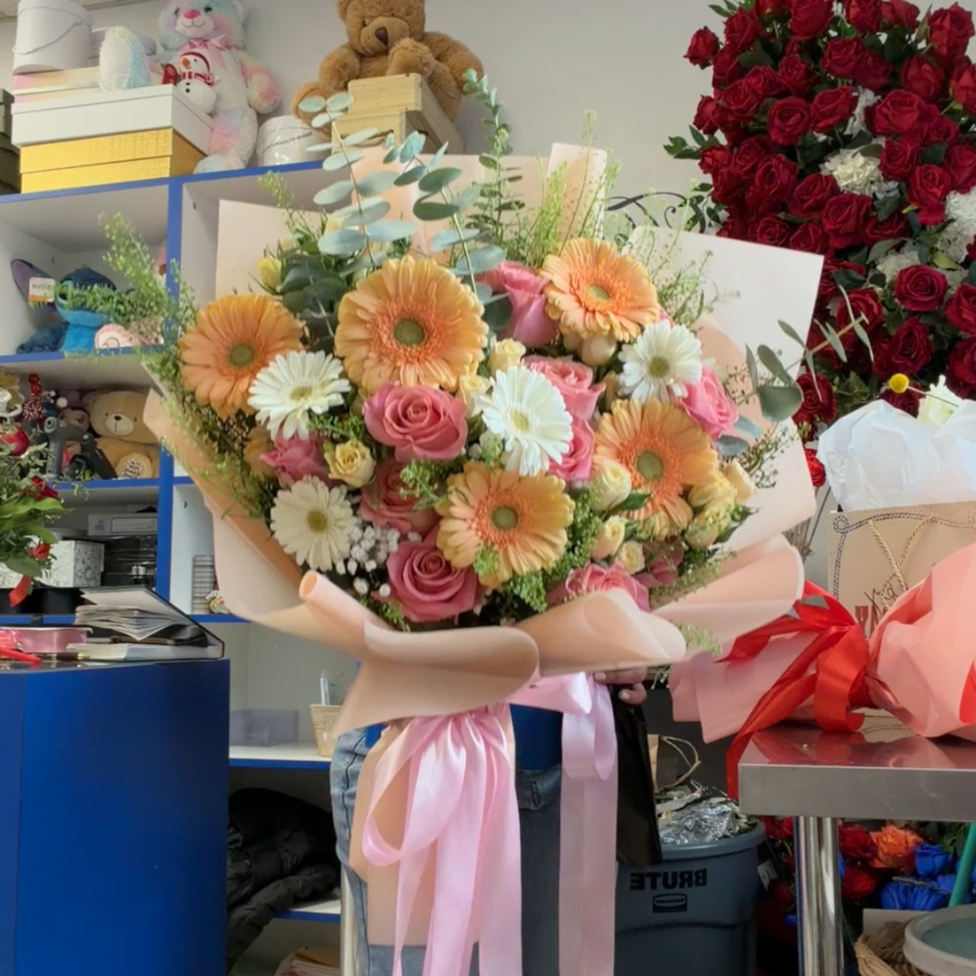 Large bouquet of pink roses and peach gerbera daisies wrapped in blush paper