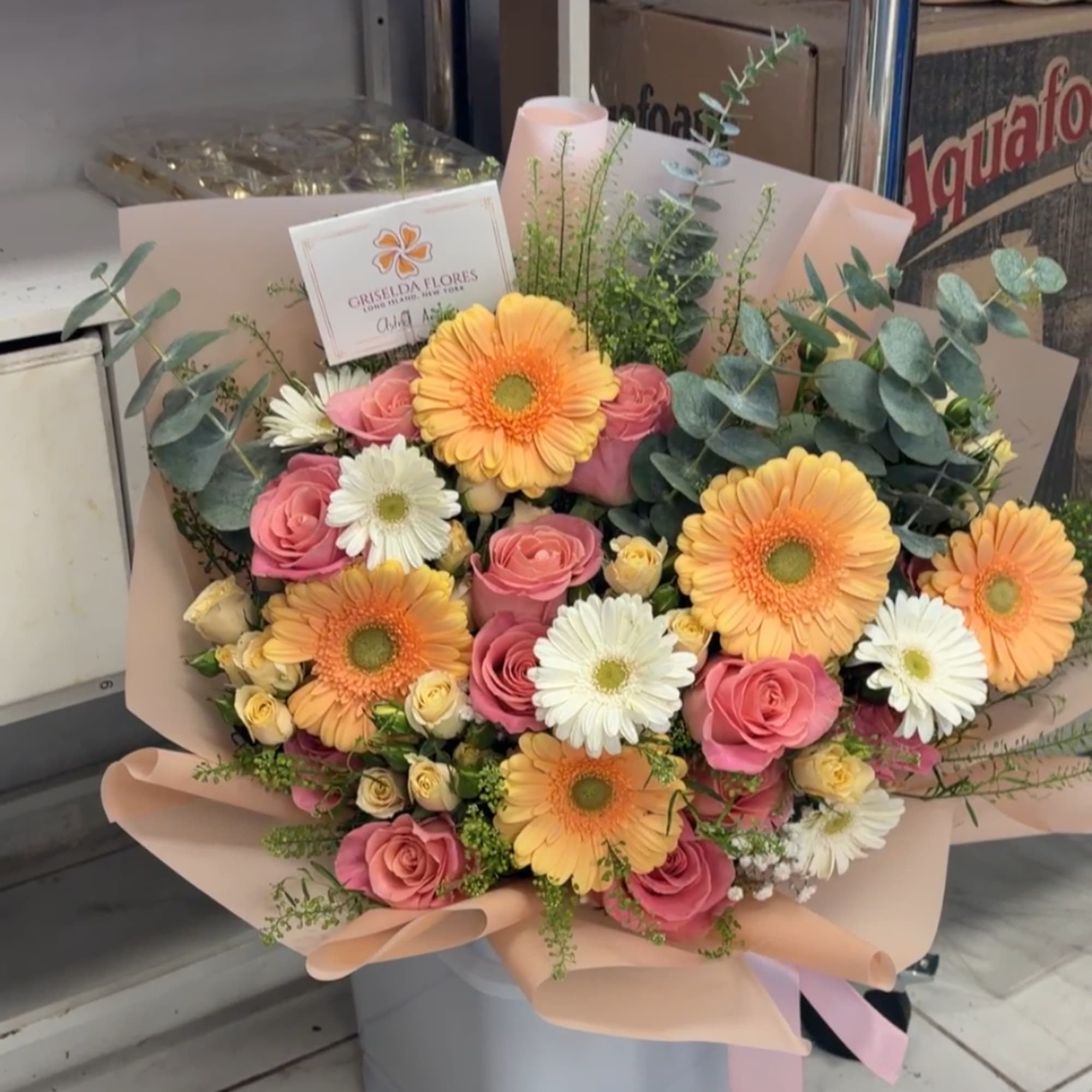 Bouquet of pink roses, orange gerbera daisies, and white daisies in blush wrap