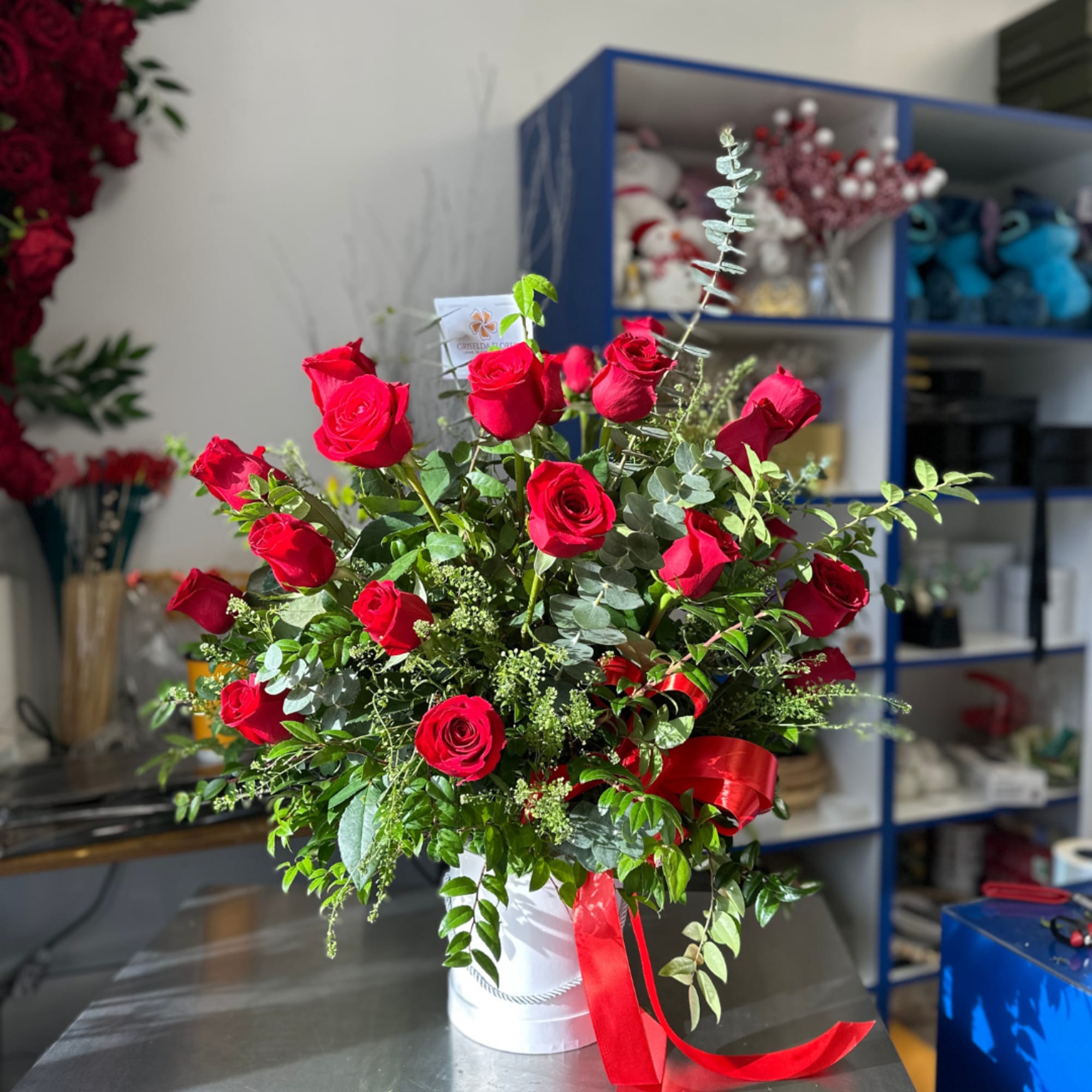 Red rose arrangement in a white hatbox with a red ribbon