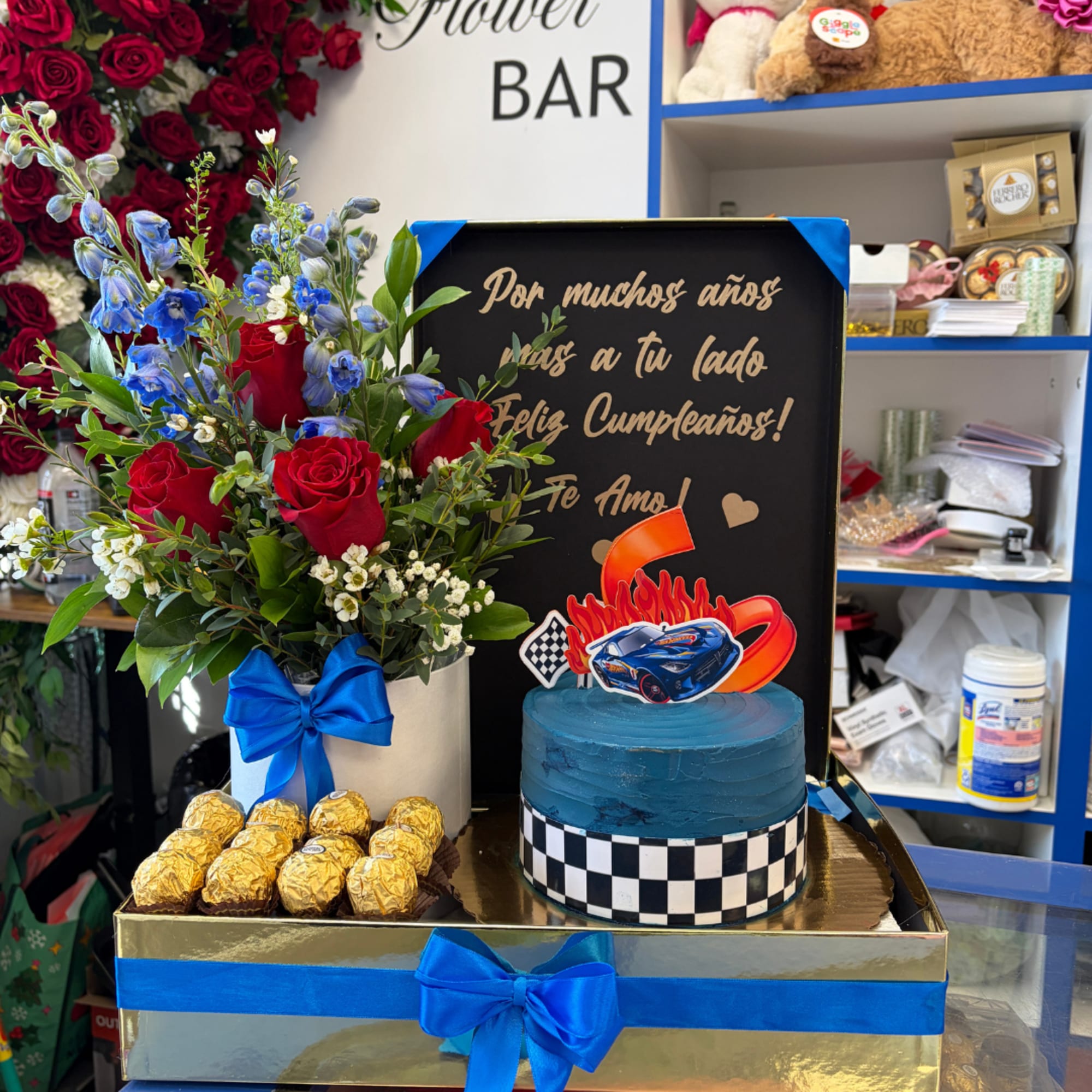 Red rose bouquet with blue flowers, chocolates, and a blue cake in a gift box