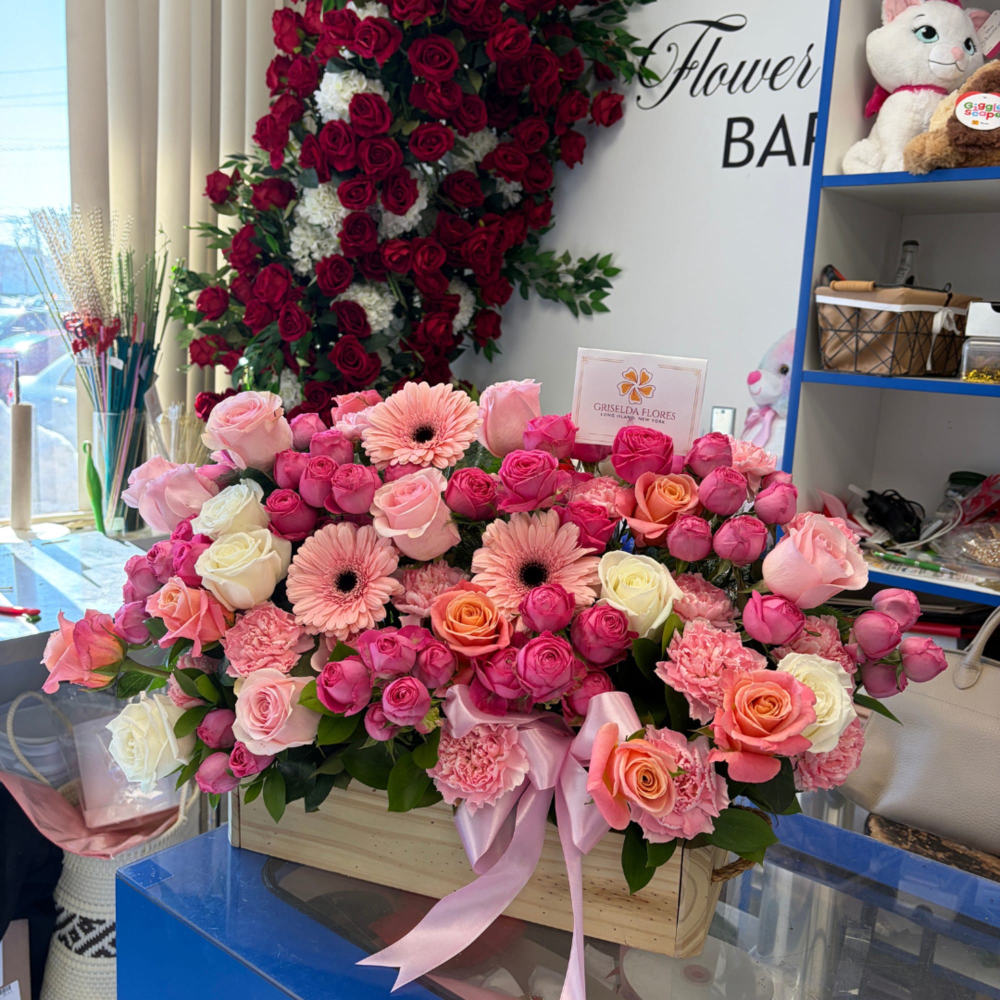 Large pink and peach rose arrangement in a wooden box with a satin ribbon