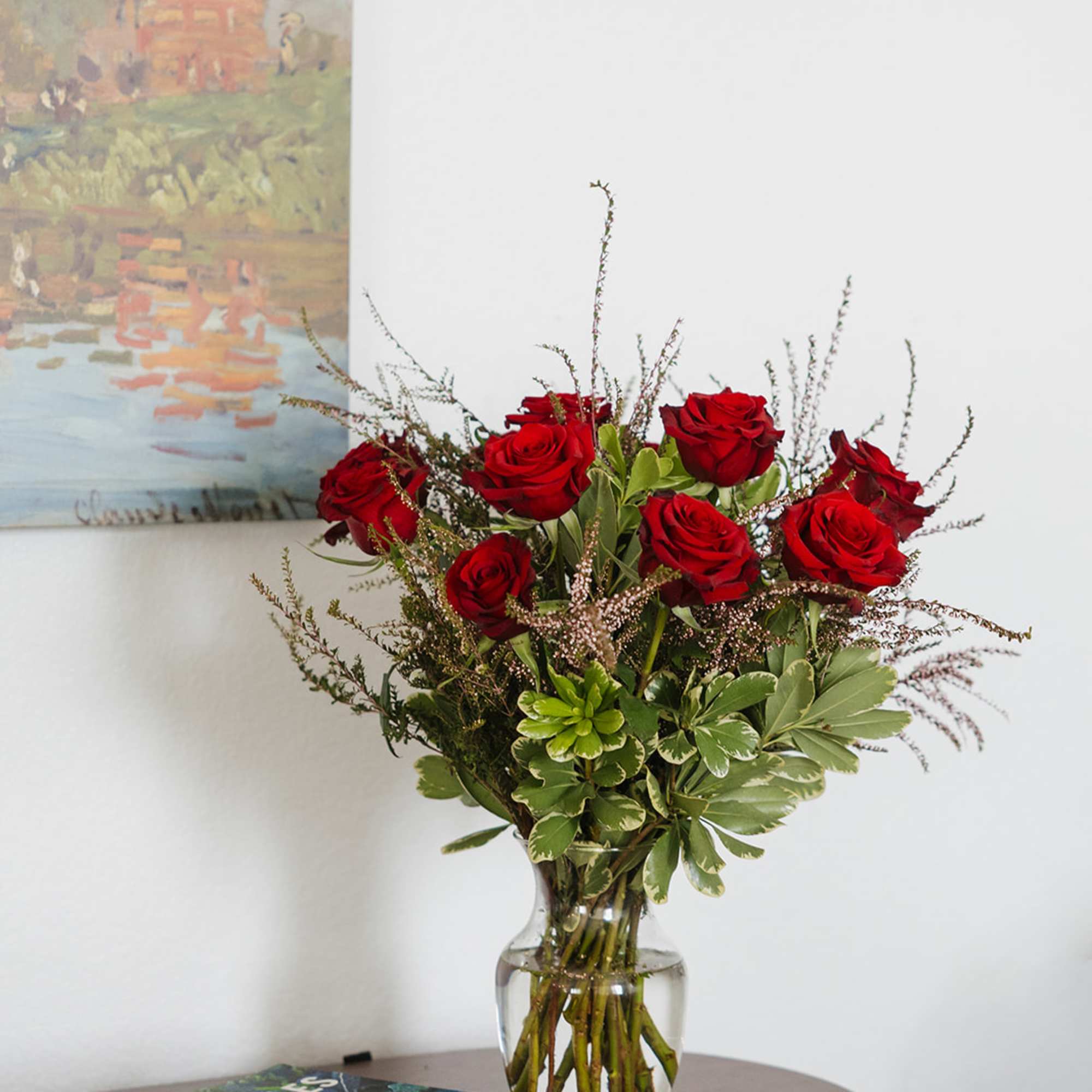 Red roses arranged in a clear glass vase on a table