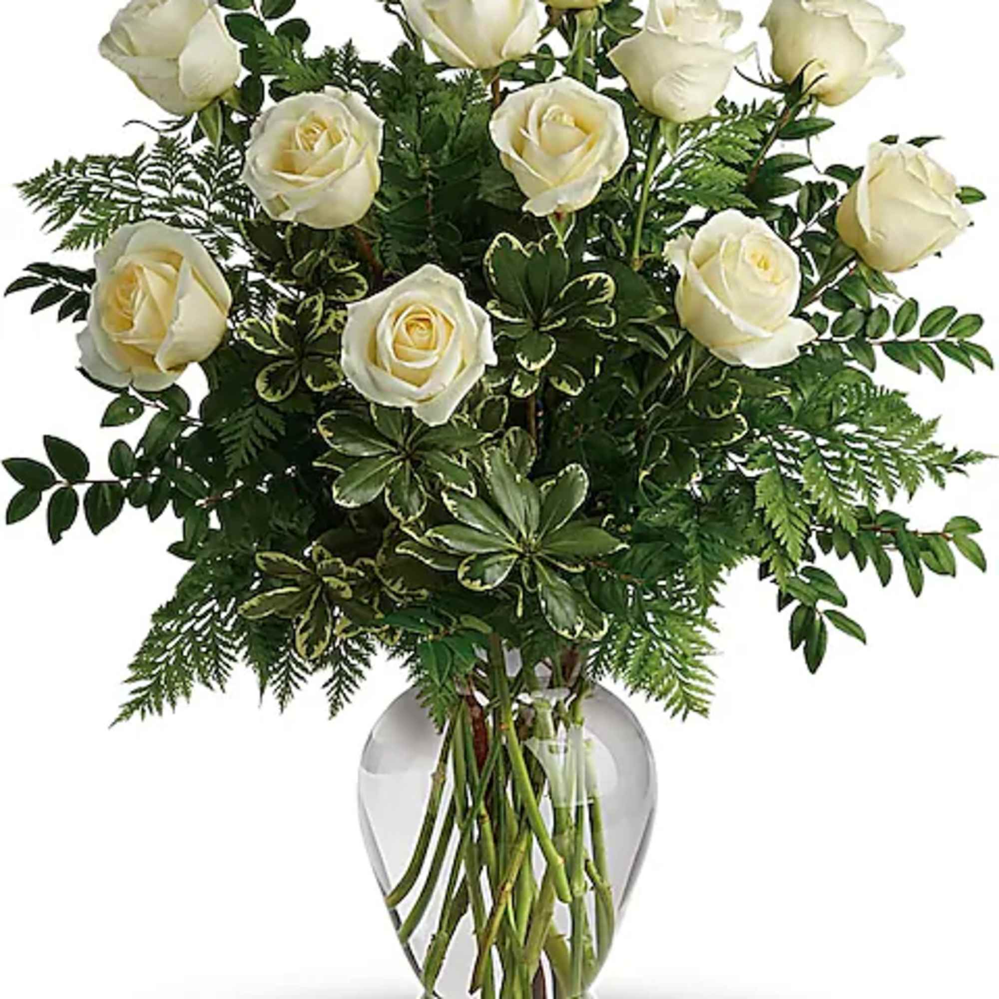 White roses arranged in a clear glass vase with mixed greenery