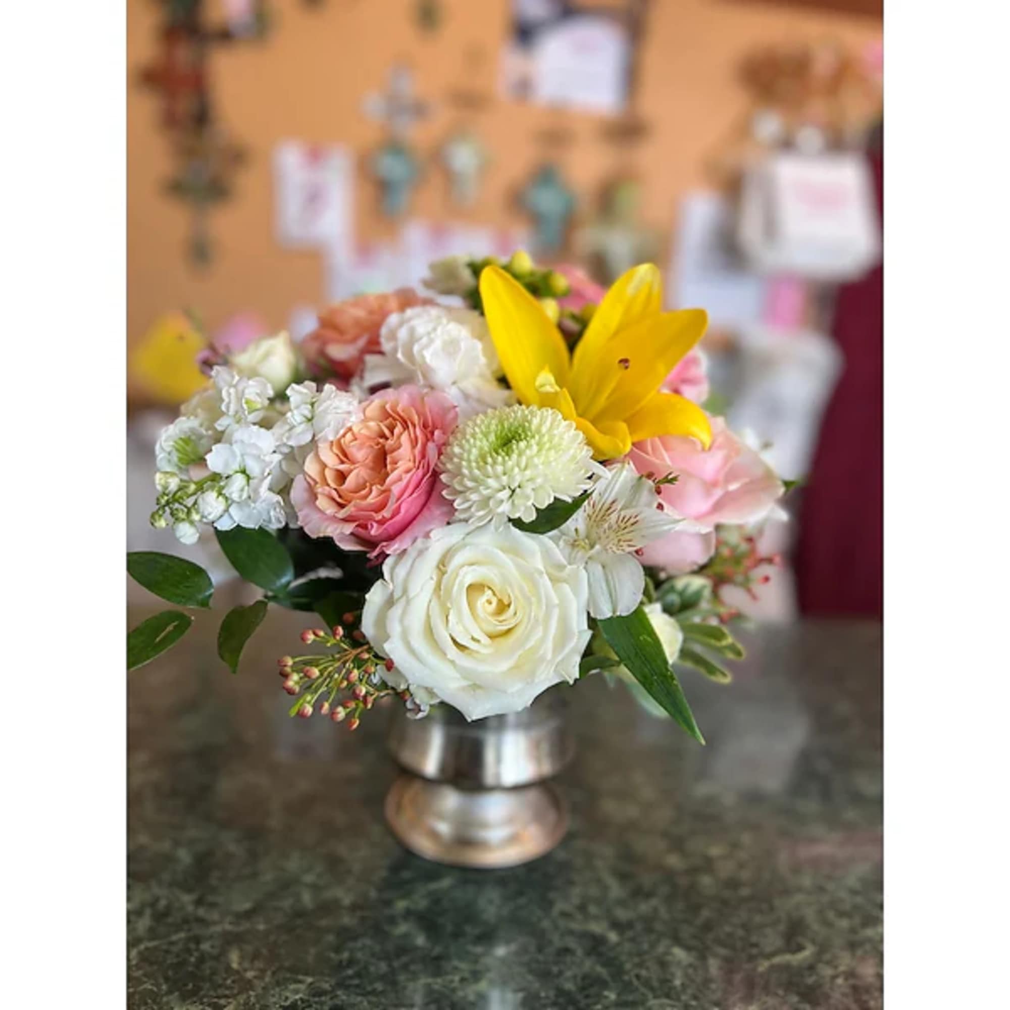 Mixed bouquet of roses, lilies, and white blooms in a silver vase