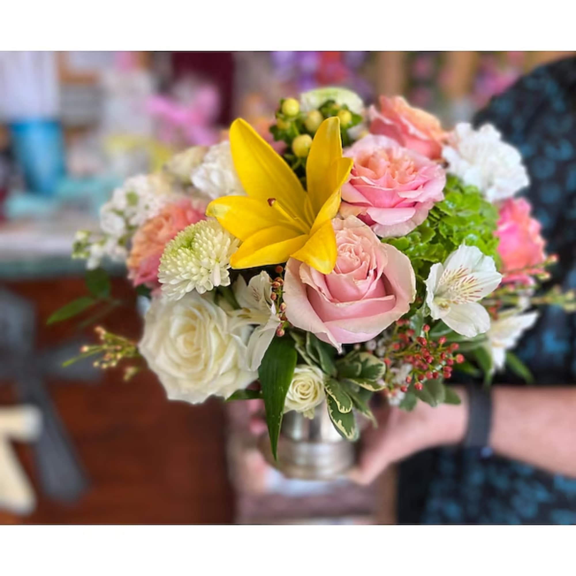 Bouquet of pink and white flowers with a yellow lily in a metal container