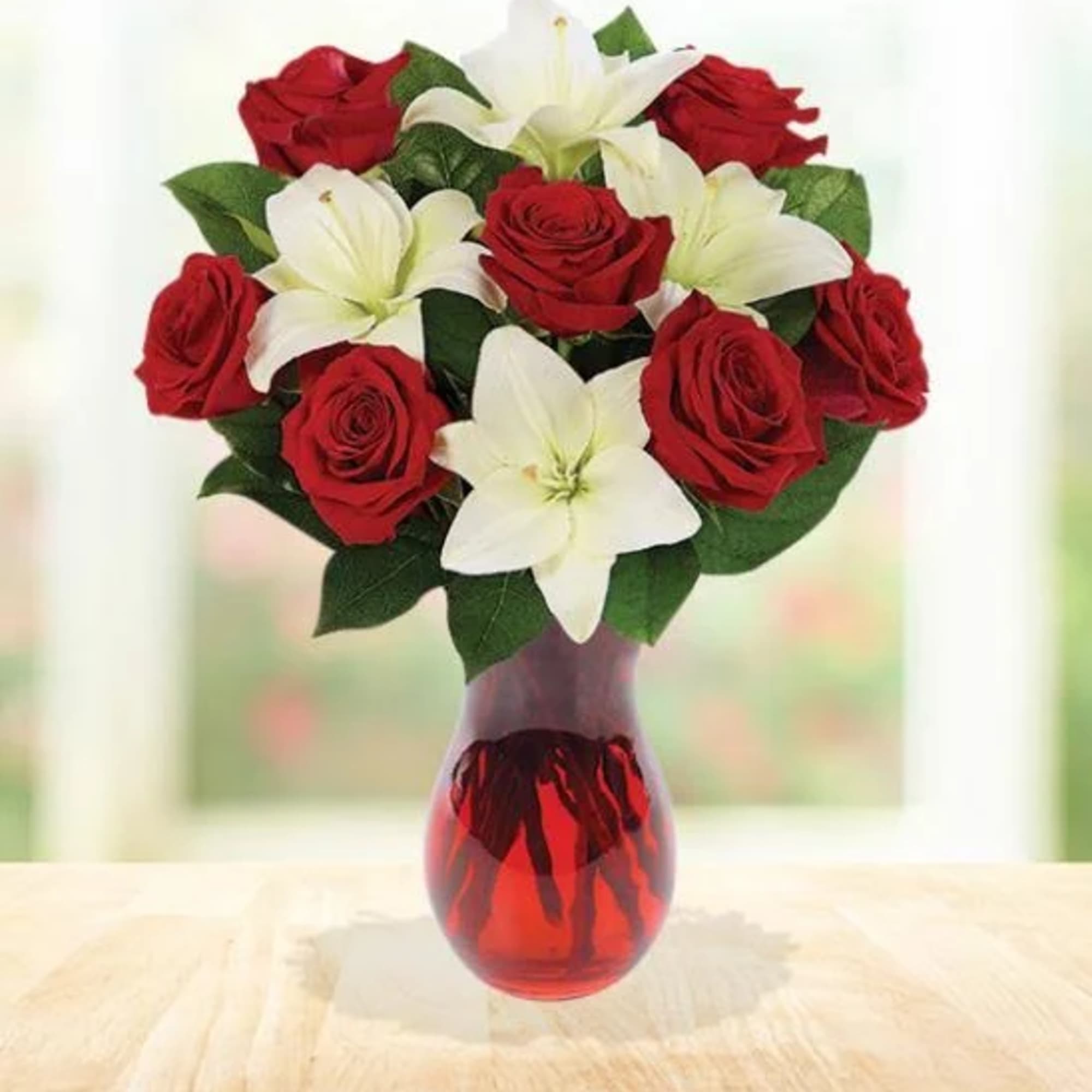 Red roses and white lilies arranged in a red glass vase