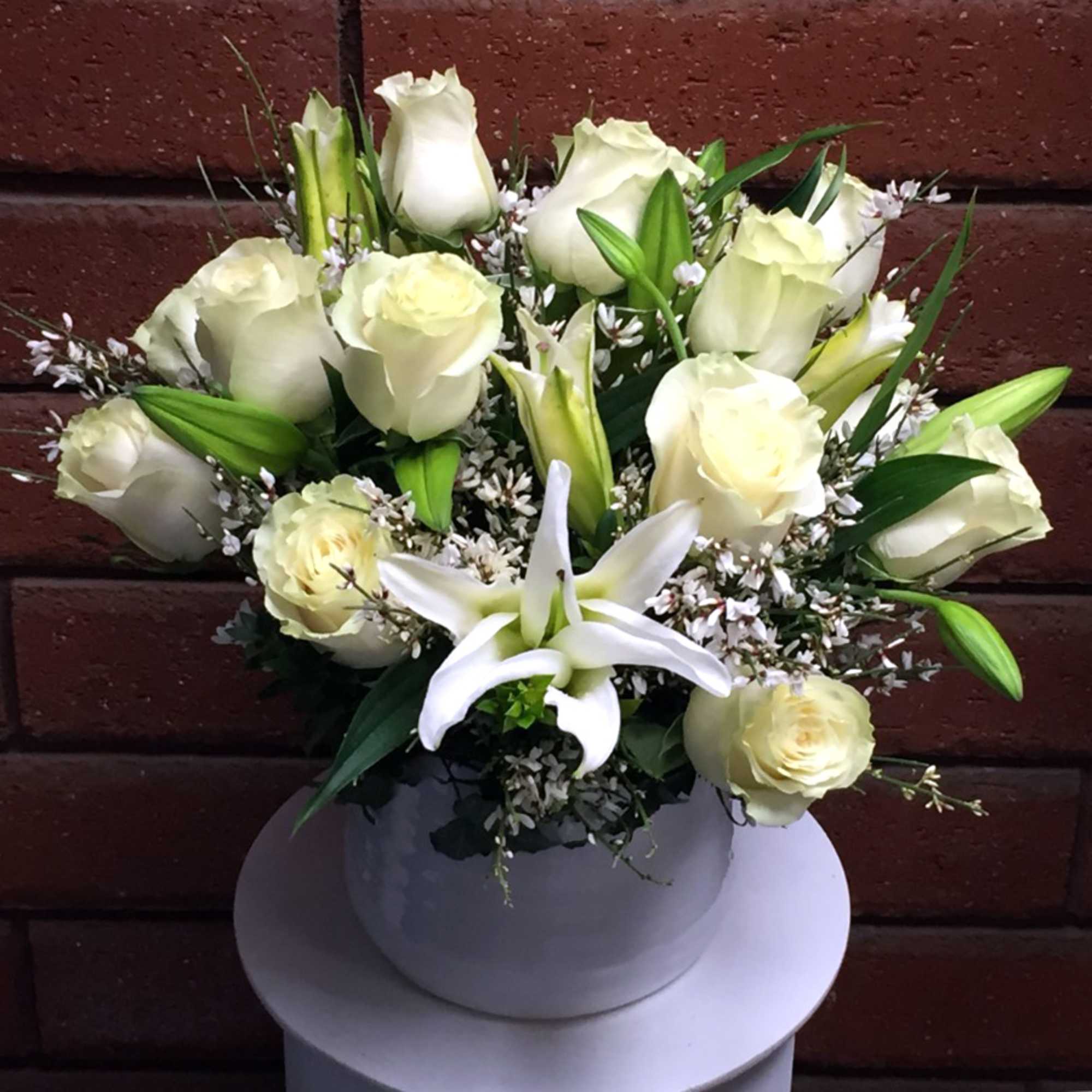 White roses and a white lily in a round vase