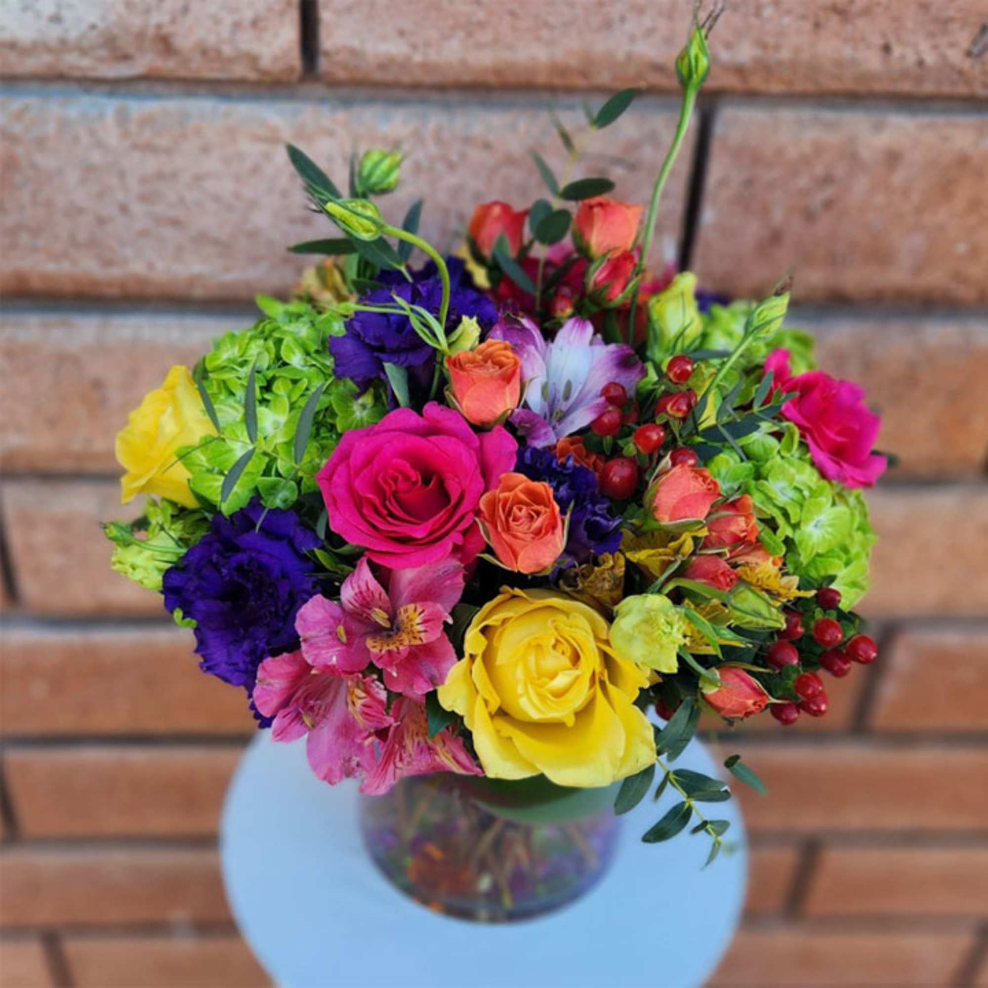 Colorful bouquet of roses, alstroemeria, and hydrangeas in a glass vase