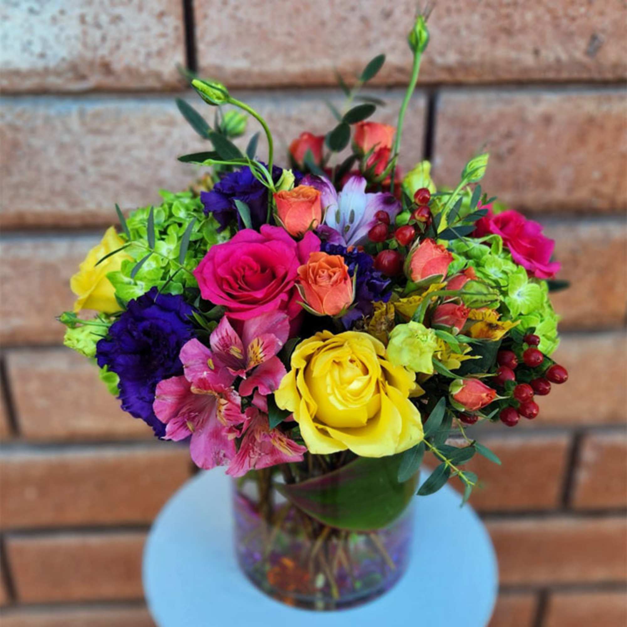Colorful bouquet of roses and mixed blooms in a glass vase