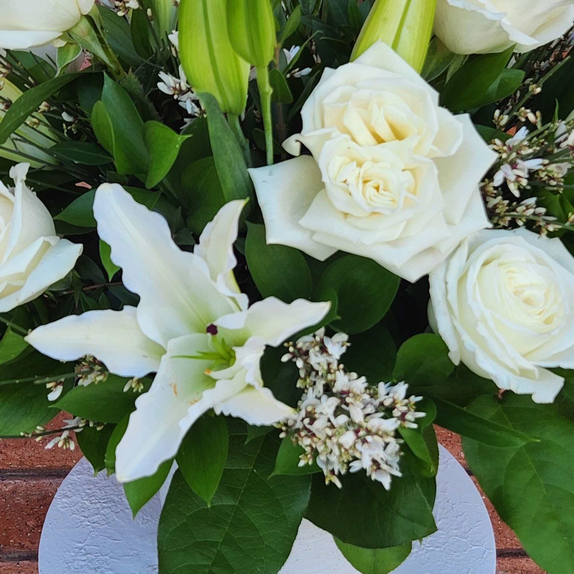 White roses and lilies arranged in a white vase