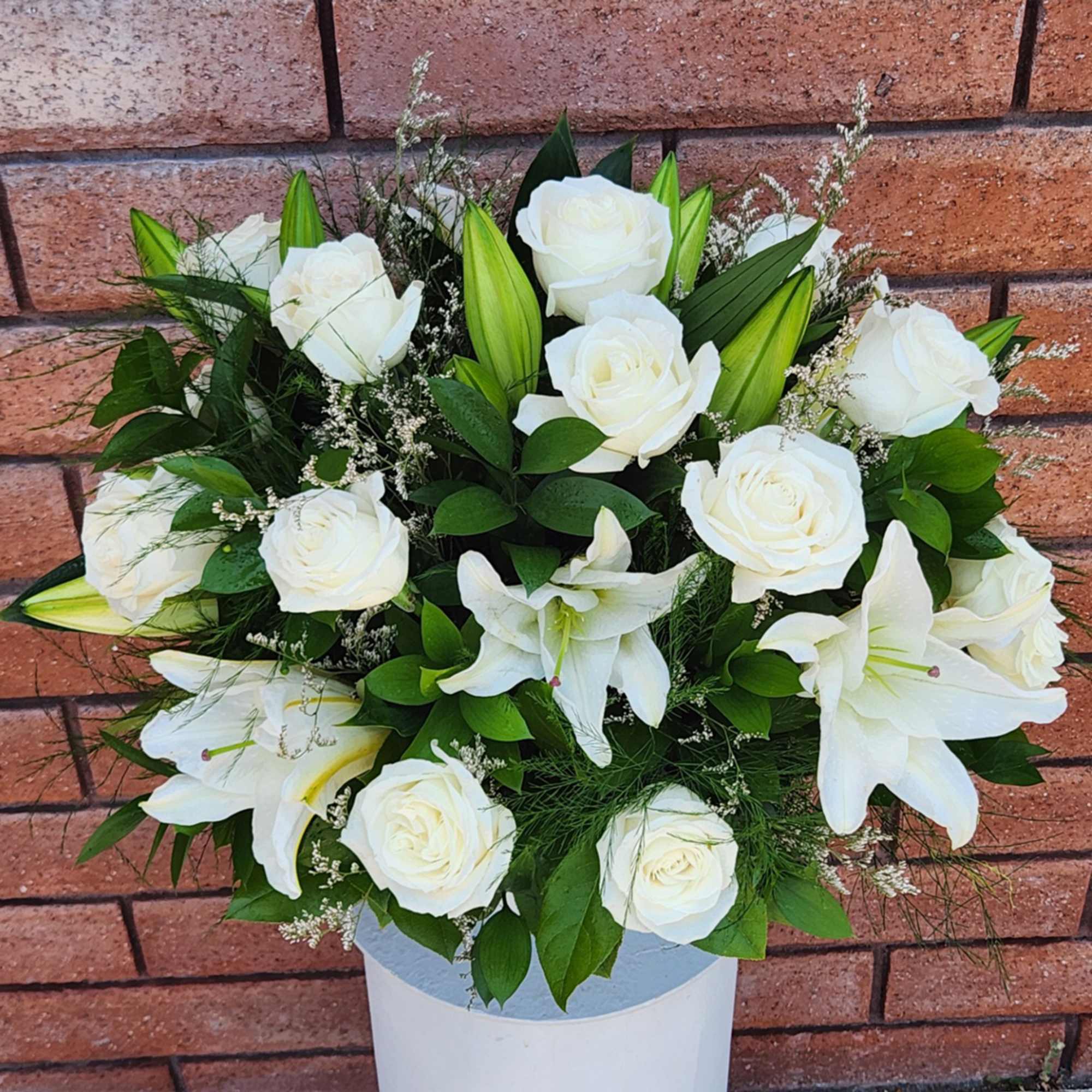 White roses and lilies arranged in a white vase