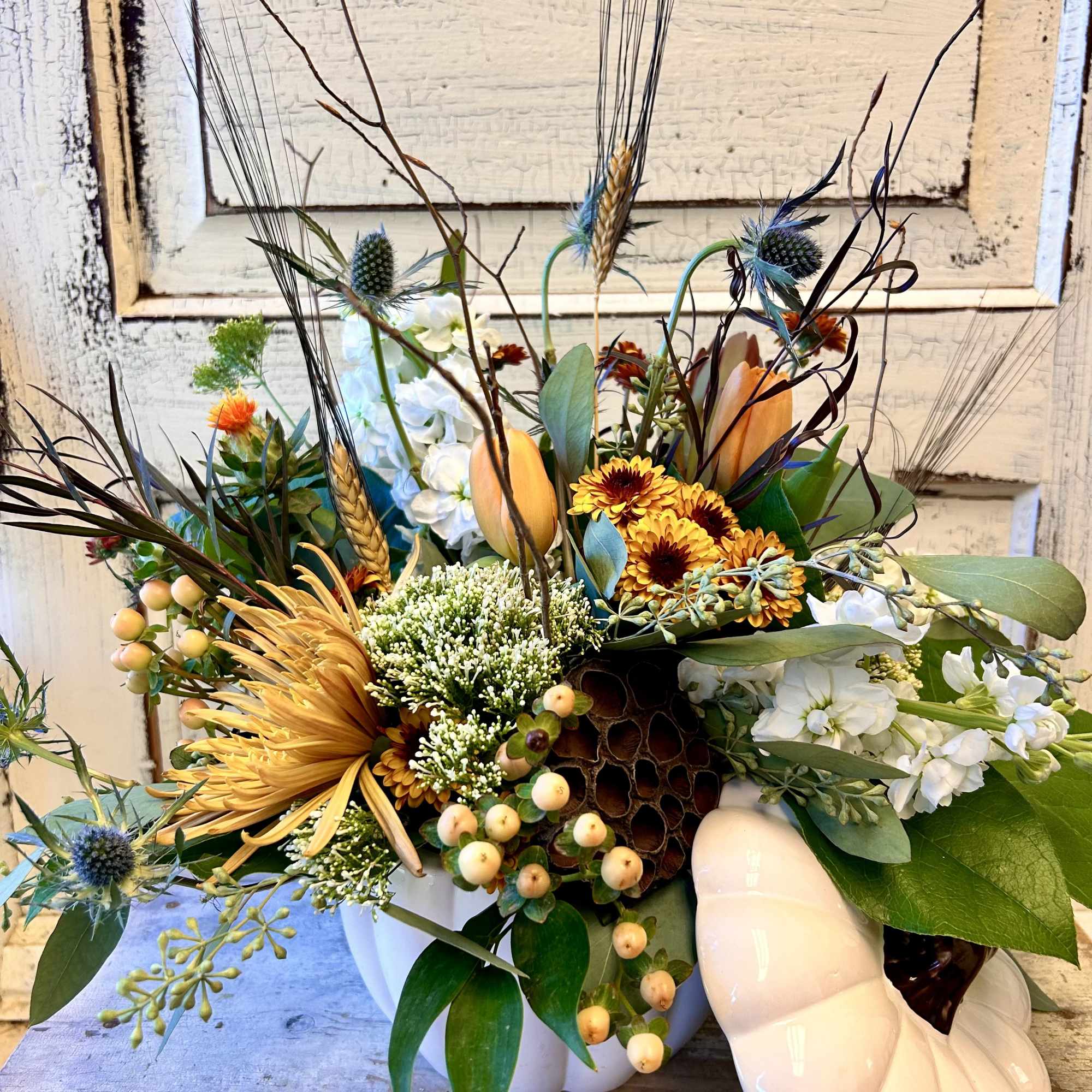 Mixed autumn bouquet in a white vase with a pale pumpkin accent