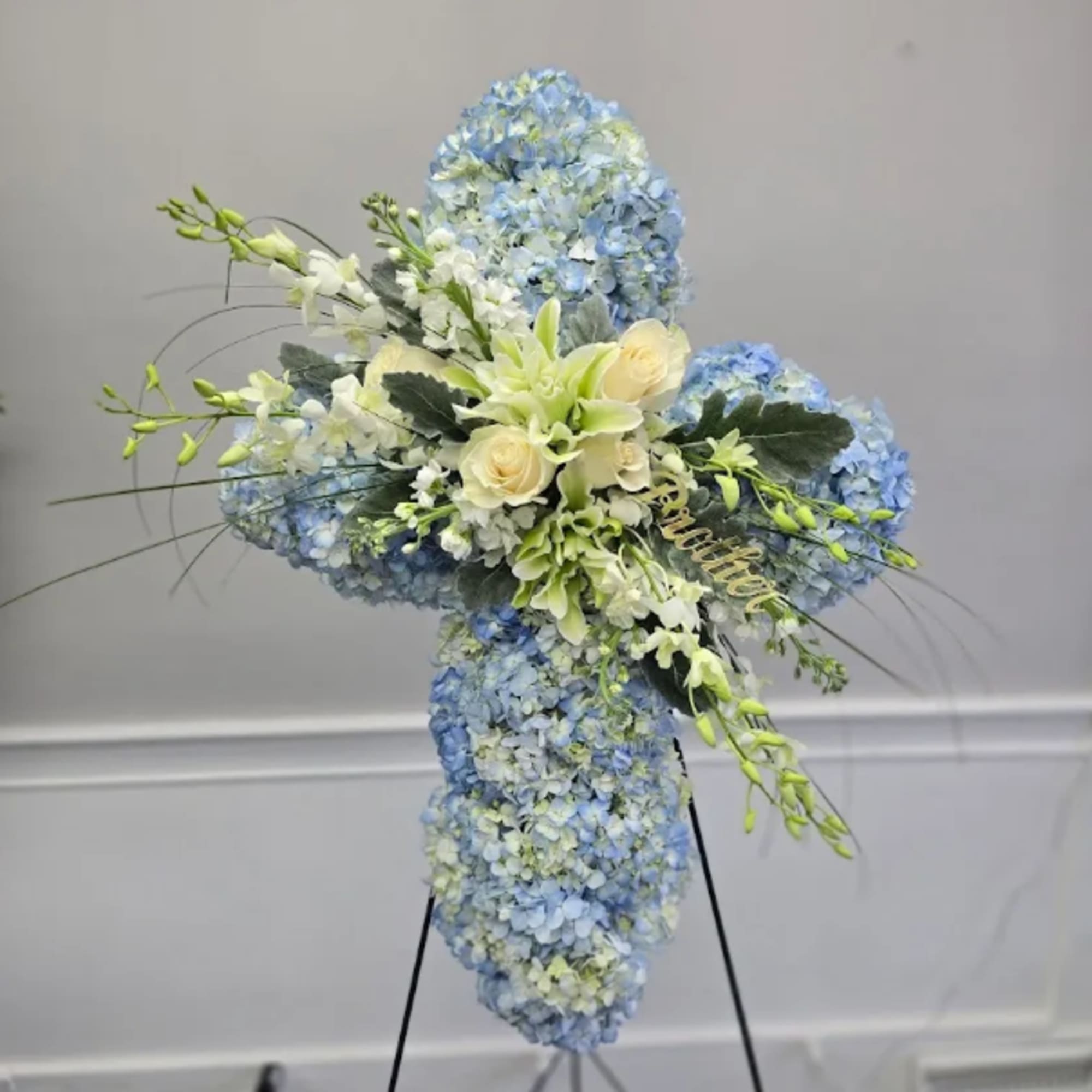 Blue and white floral standing cross arrangement on an easel