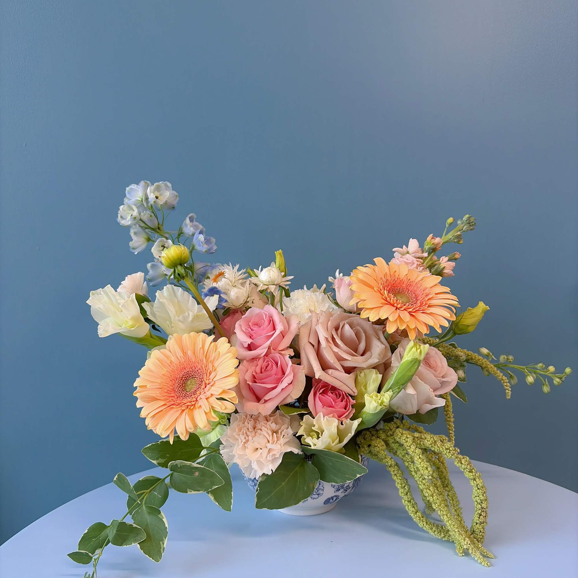 Pastel bouquet with roses, gerbera daisies, and mixed blooms in a ceramic bowl