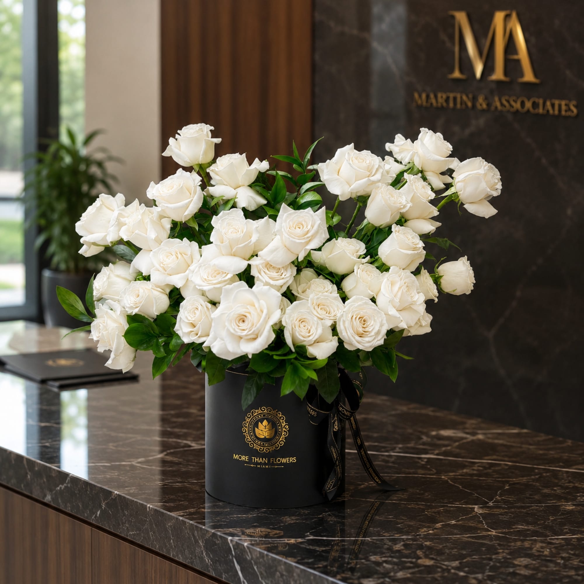 White roses arranged in a black hatbox on a marble counter
