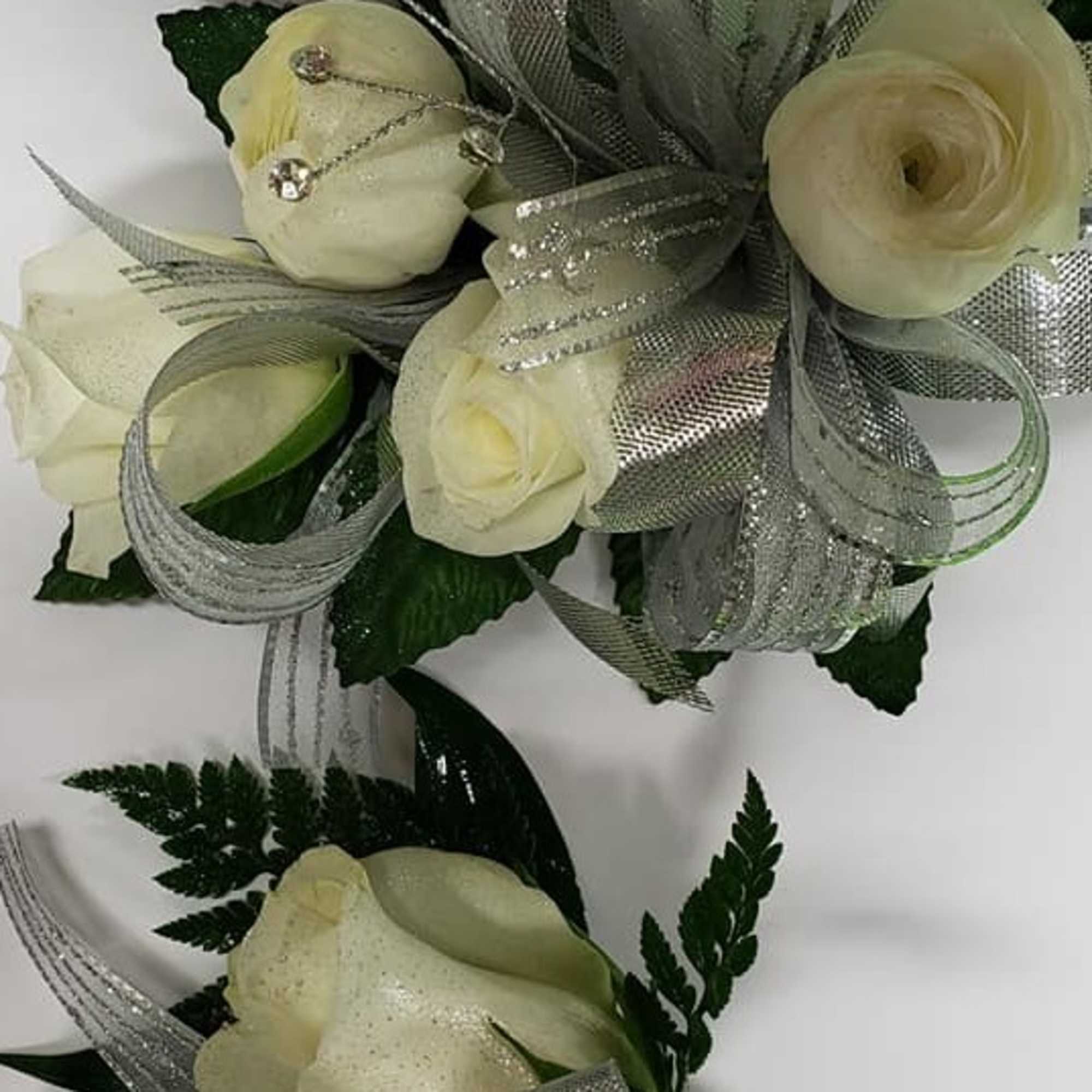 White rose corsage and boutonniere with silver glitter ribbon and crystal accents.
