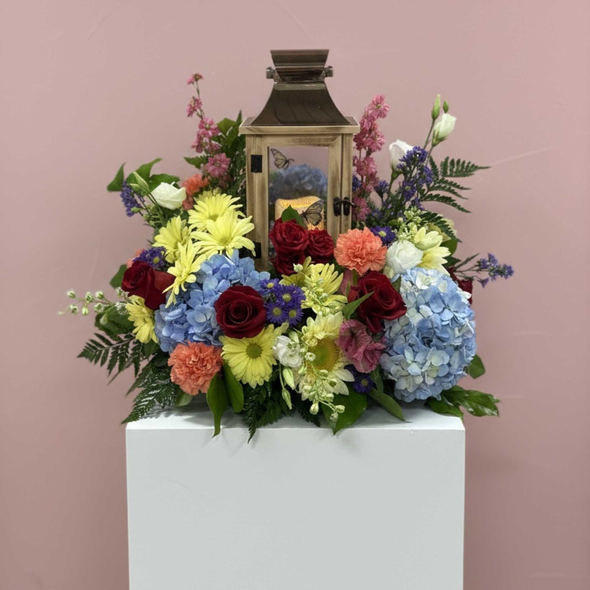 Lantern surrounded by colorful flowers on a pedestal
