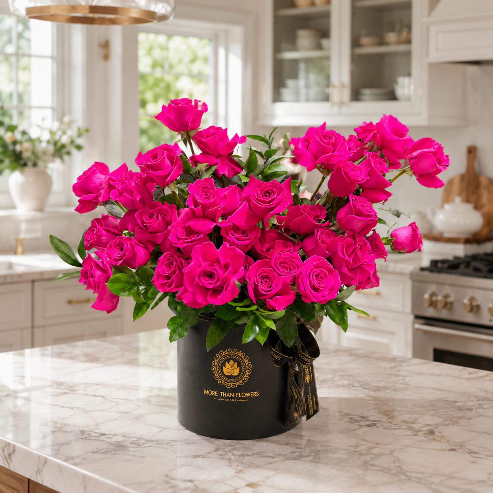 Hot pink roses arranged in a black hatbox on a kitchen counter