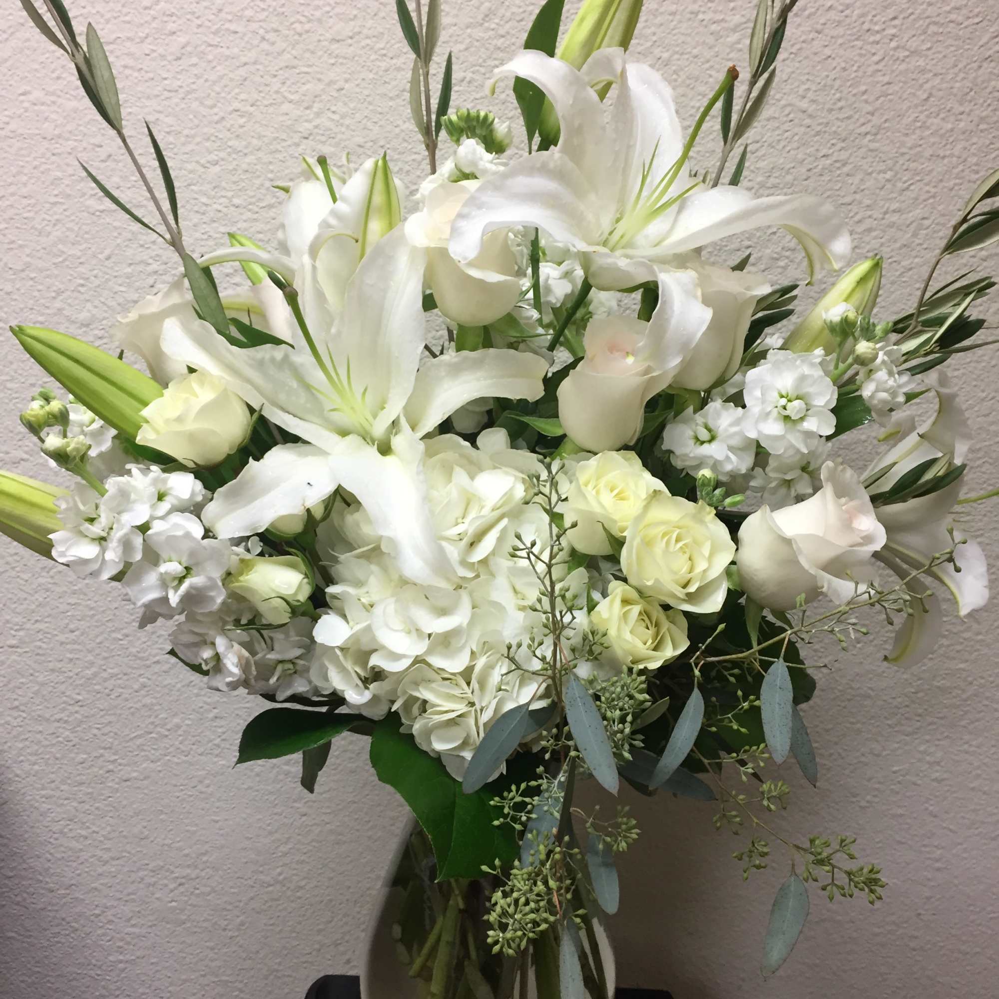 White lilies and roses arranged in a glass vase.
