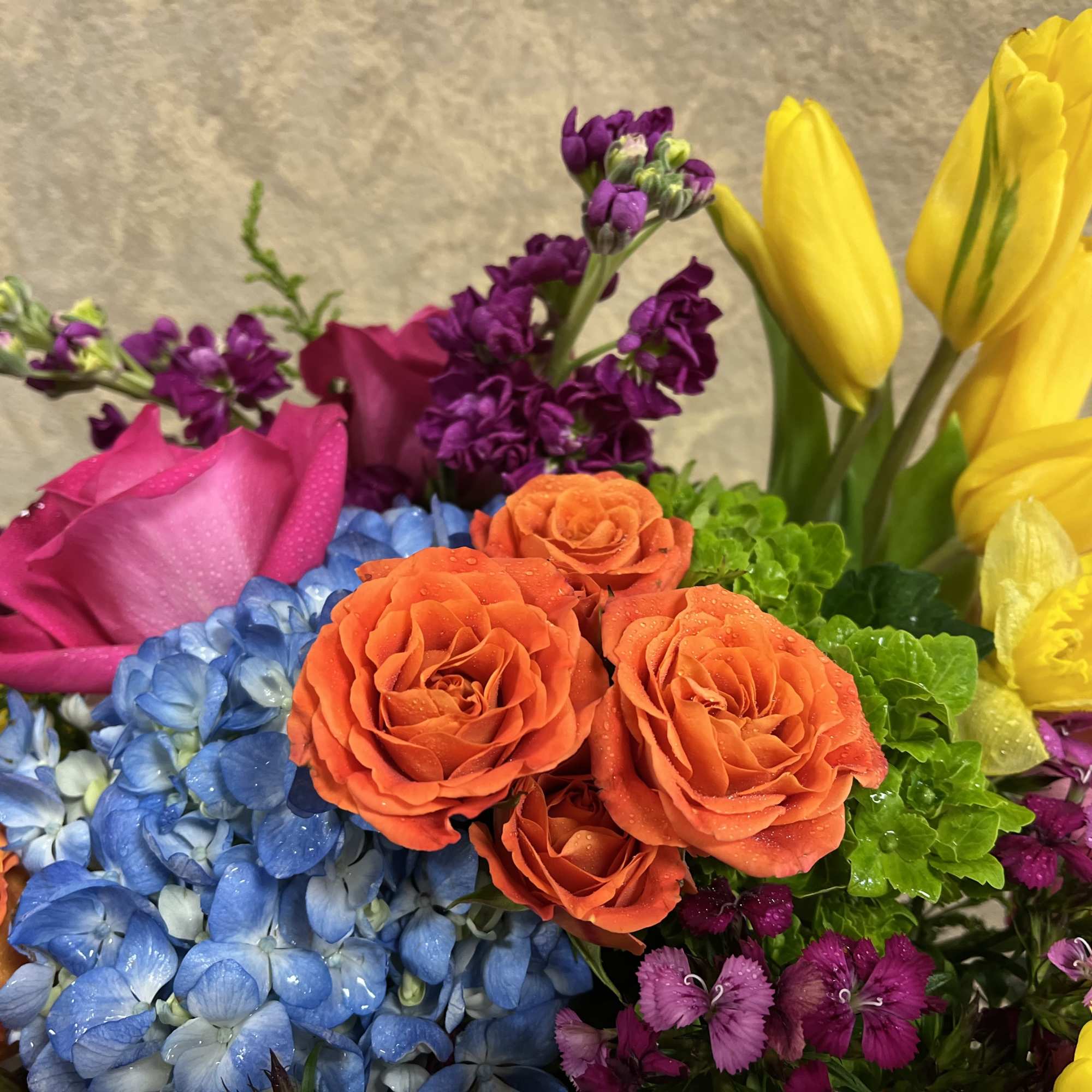 Colorful bouquet with orange roses, blue hydrangeas, and yellow tulips