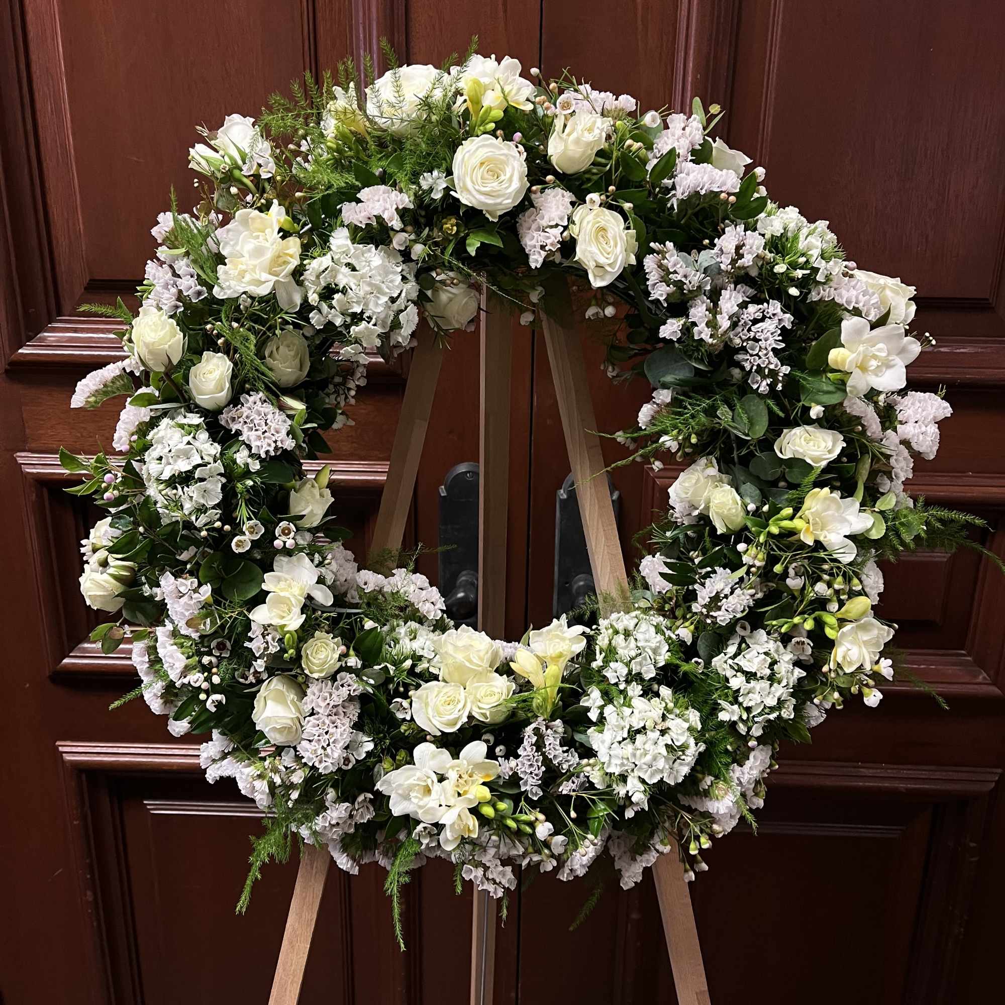 Large white floral wreath on a wooden easel