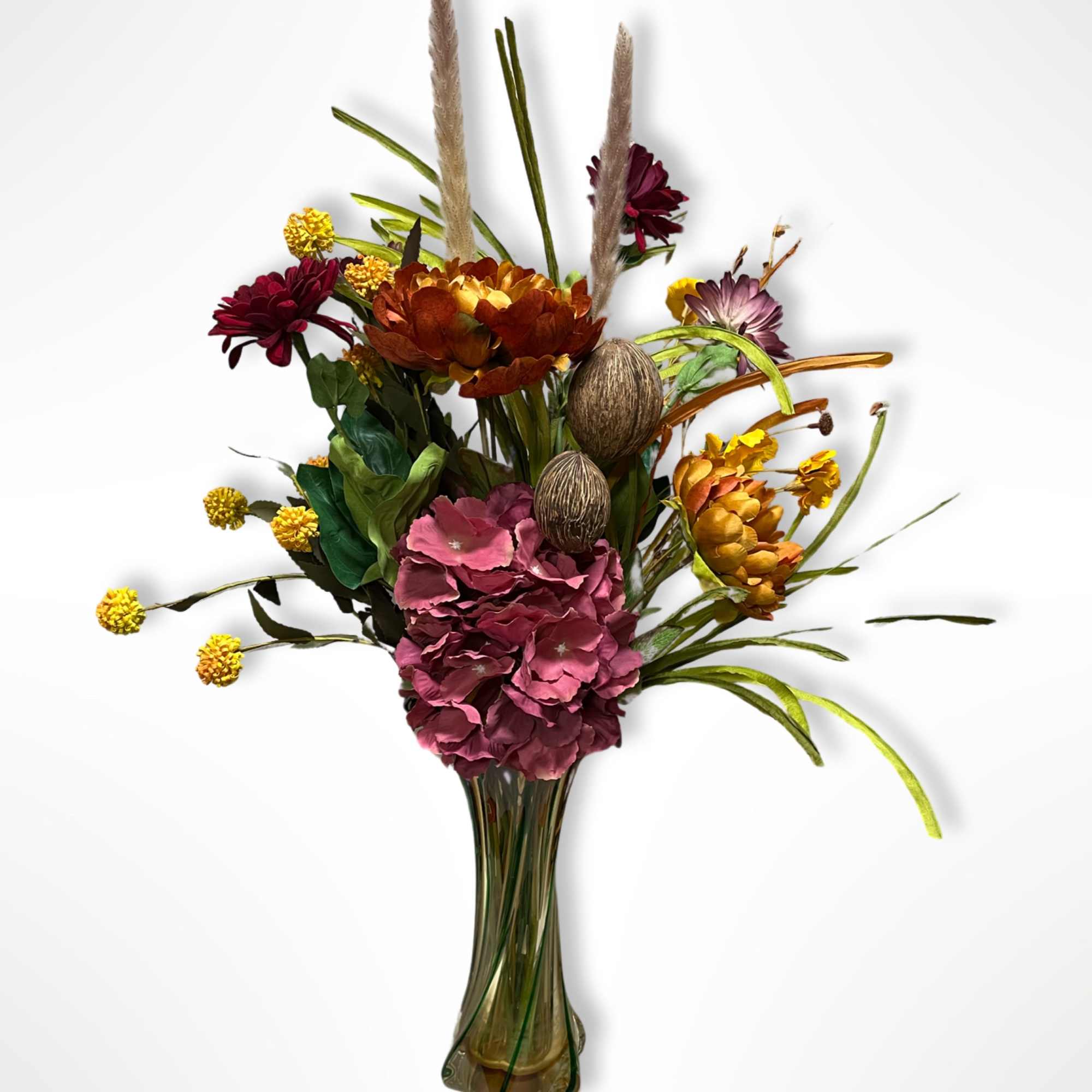 Mixed floral arrangement in a tall glass vase with burgundy, pink, and gold blooms