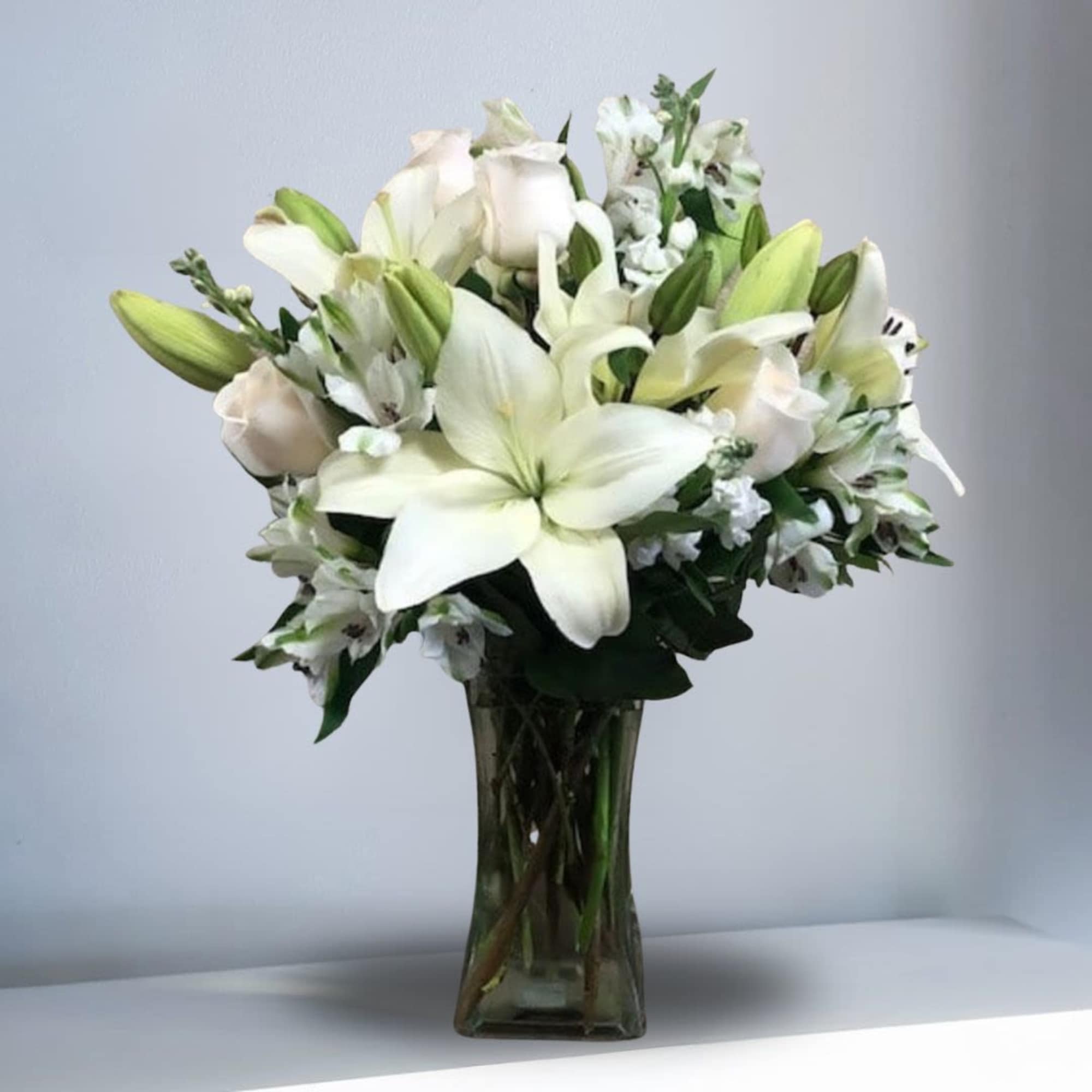 White lilies and roses arranged in a clear glass vase, photo 2 of 2