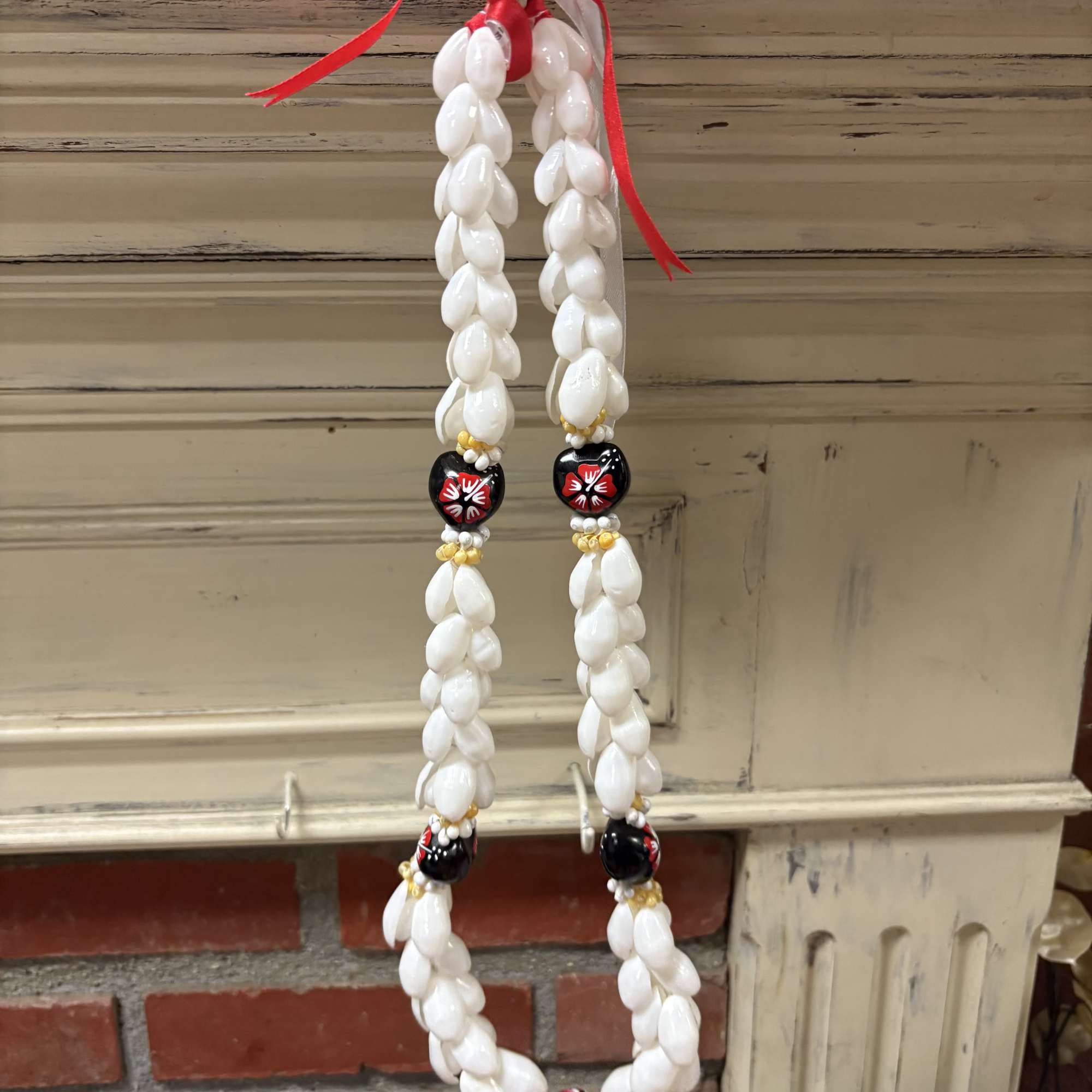 Shell bead garland with red ribbon hanging on a mantel