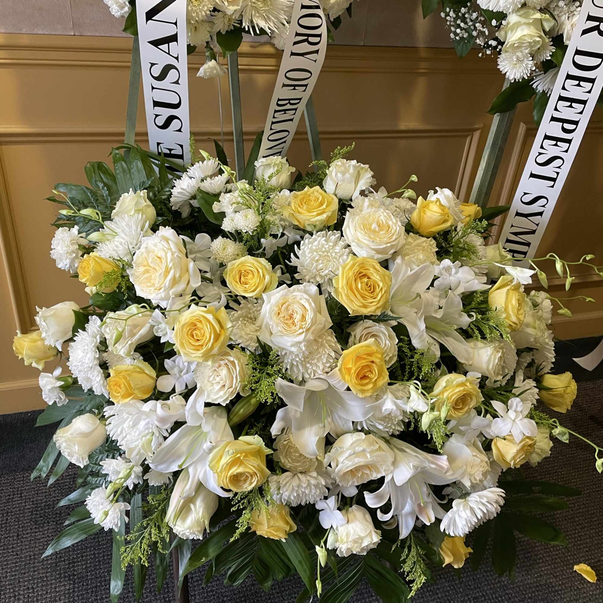 White and yellow funeral wreaths with memorial ribbons
