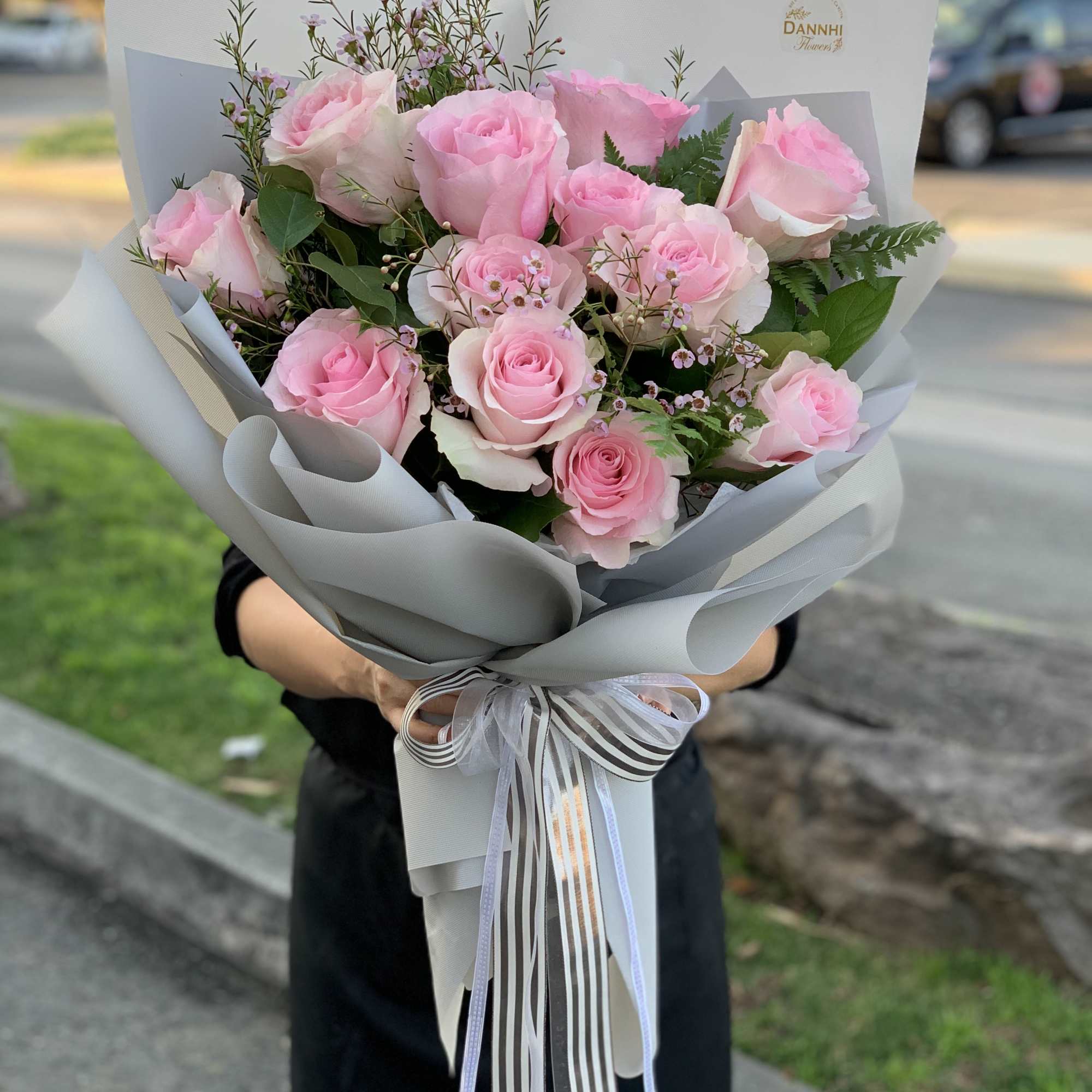 Bouquet of pink roses wrapped in gray paper with ribbon