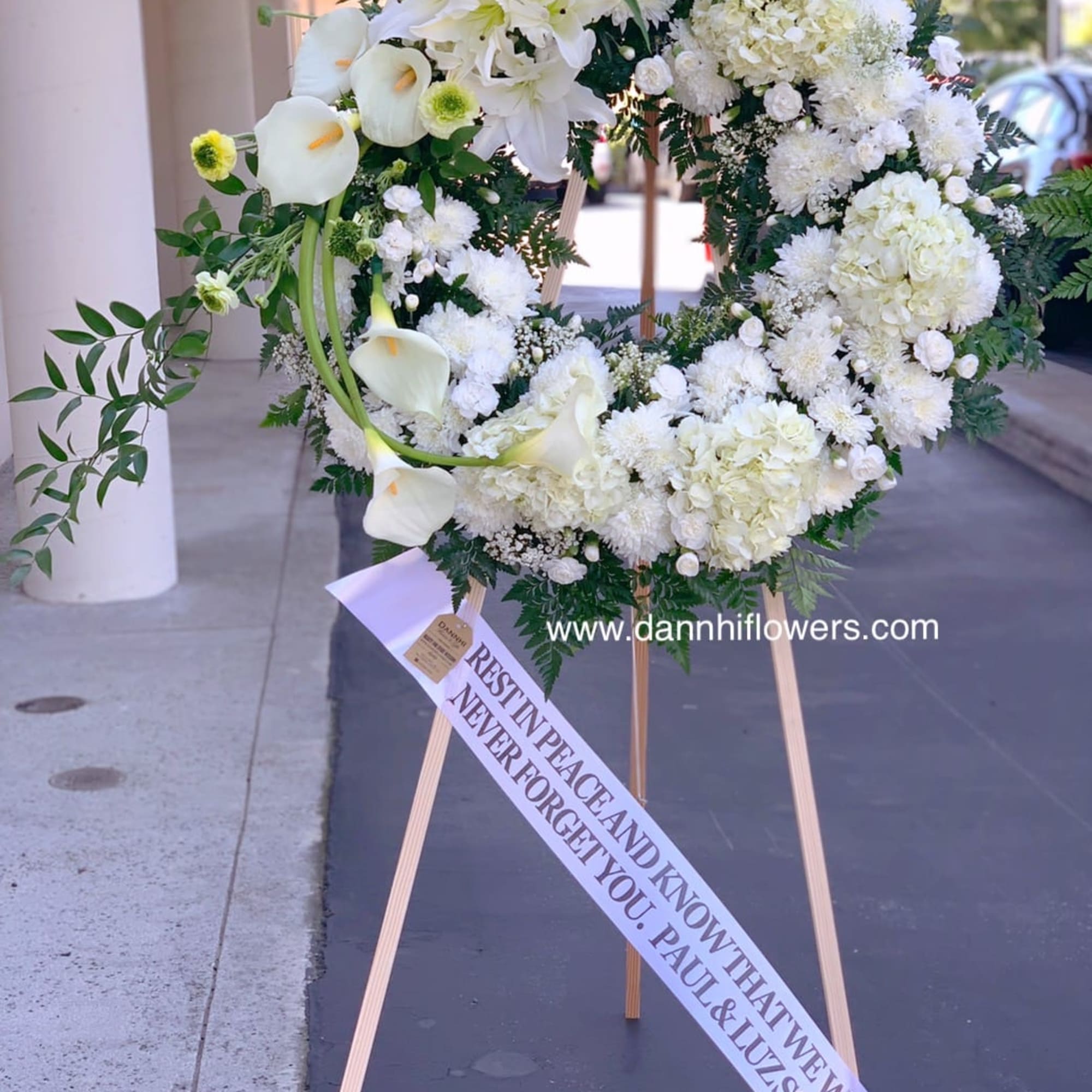 White funeral wreath on a wooden easel with a memorial ribbon