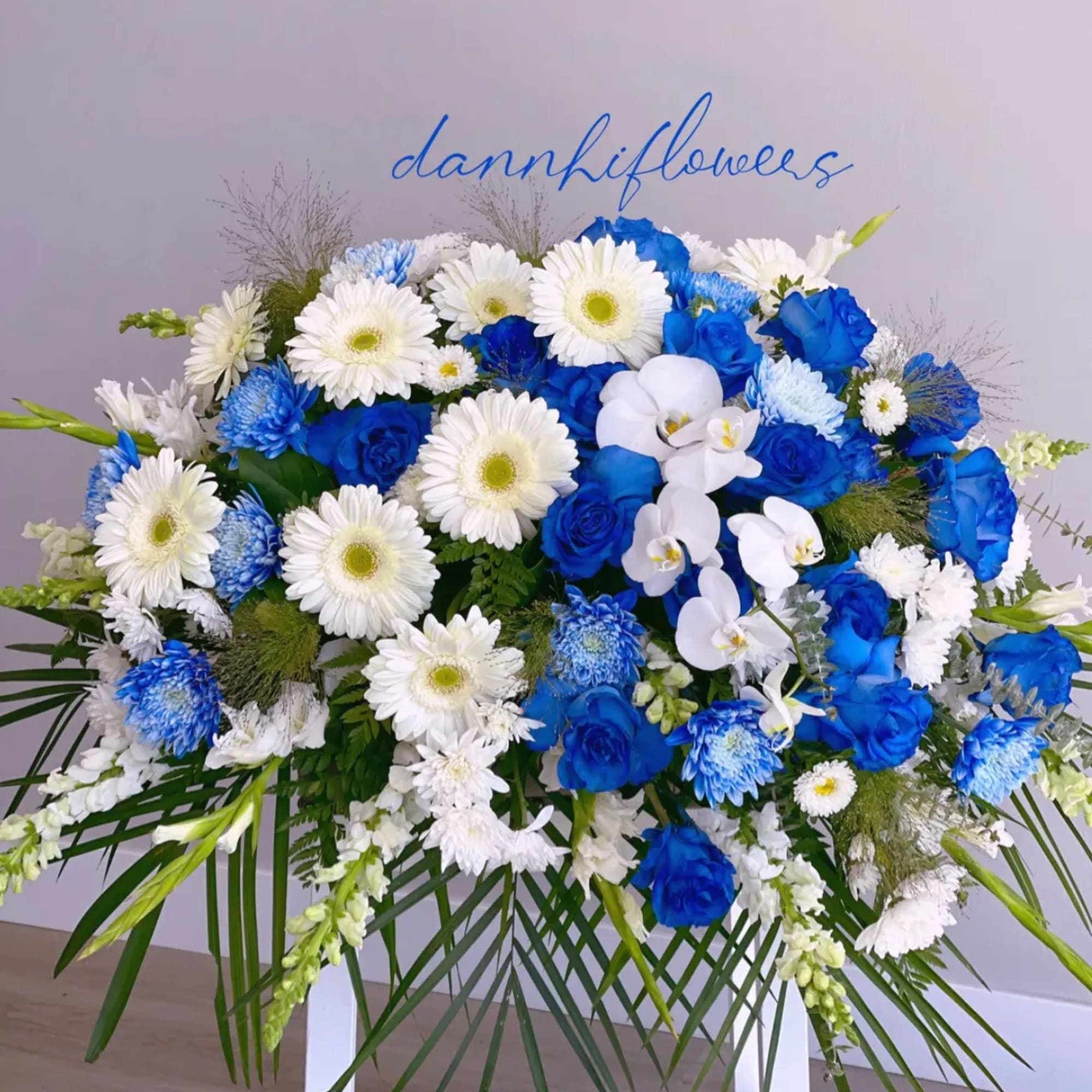 Blue and white floral spray with roses, daisies, and orchids