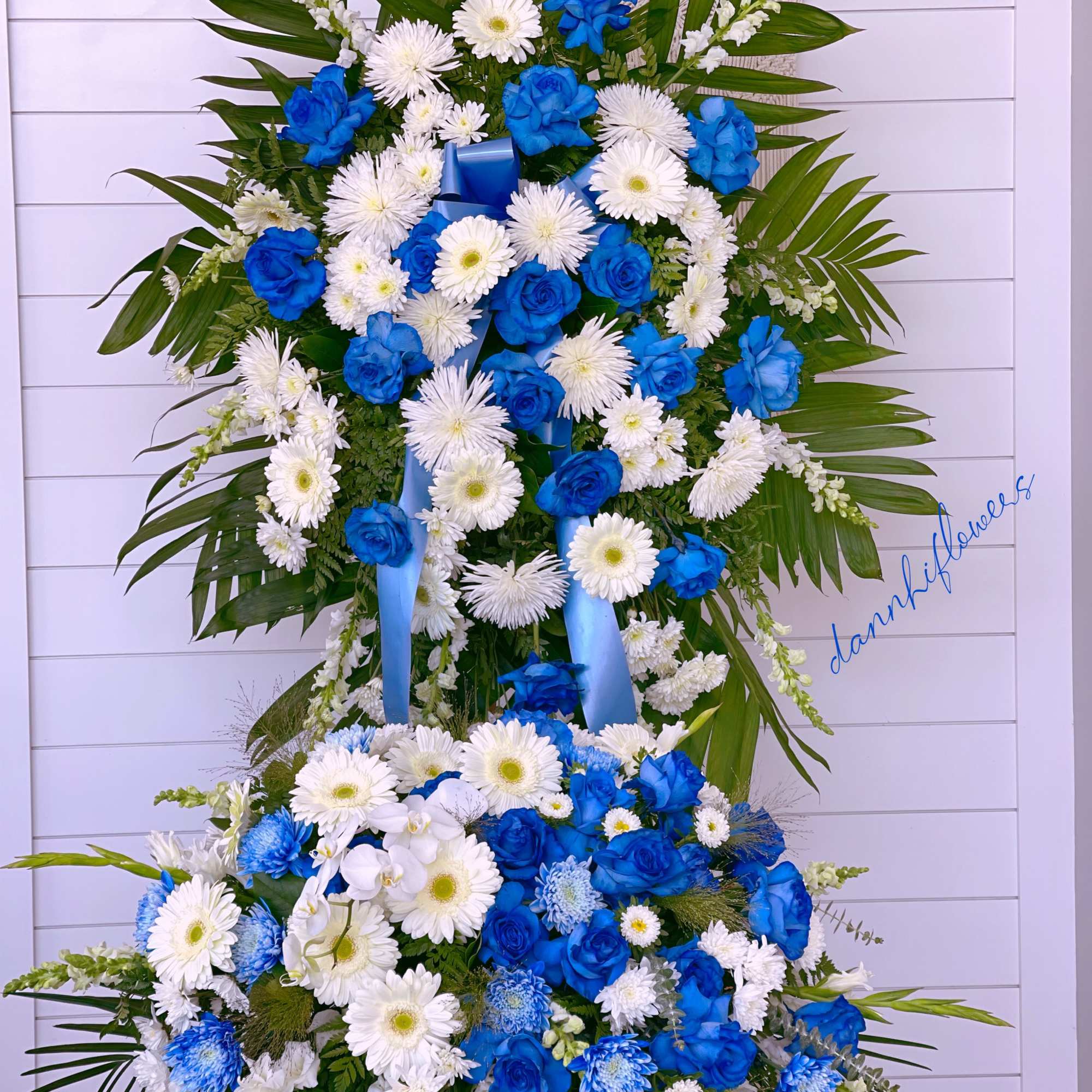 Large blue and white floral standing spray with ribbon on an easel