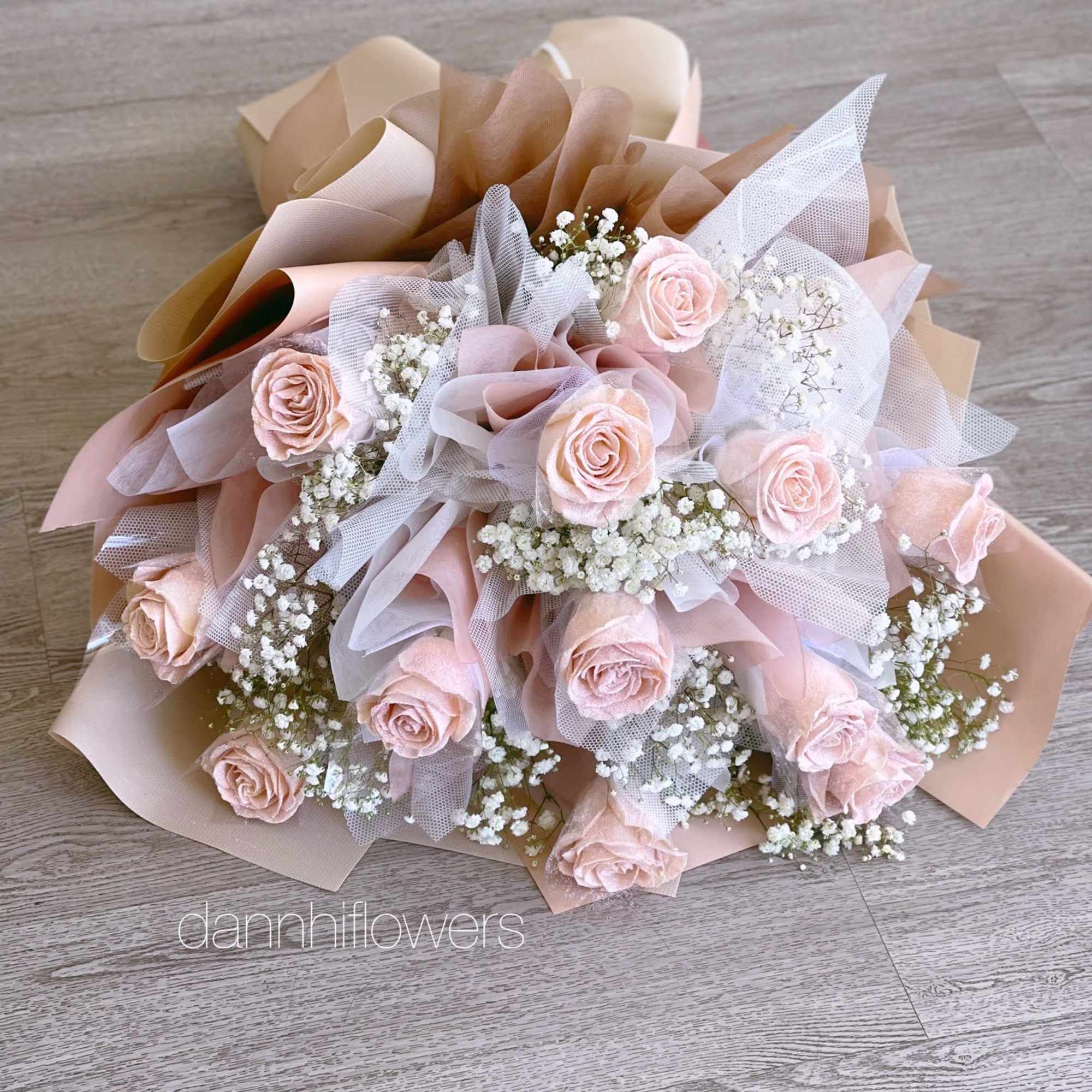 Bouquet of pale pink roses with white baby's breath in blush and beige wrap