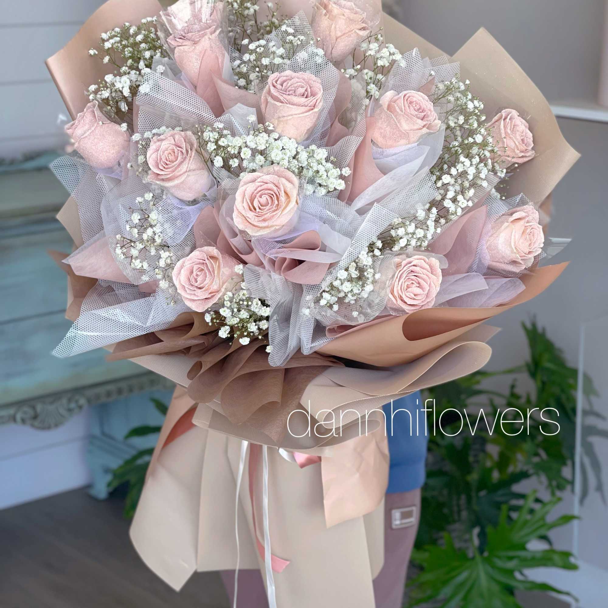 Bouquet of pale pink roses with white baby's breath in blush wrapping