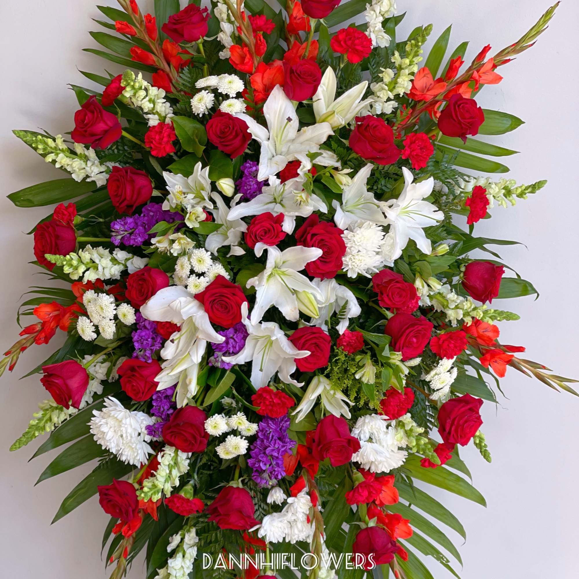 Large standing spray of red roses, white lilies, and mixed blooms