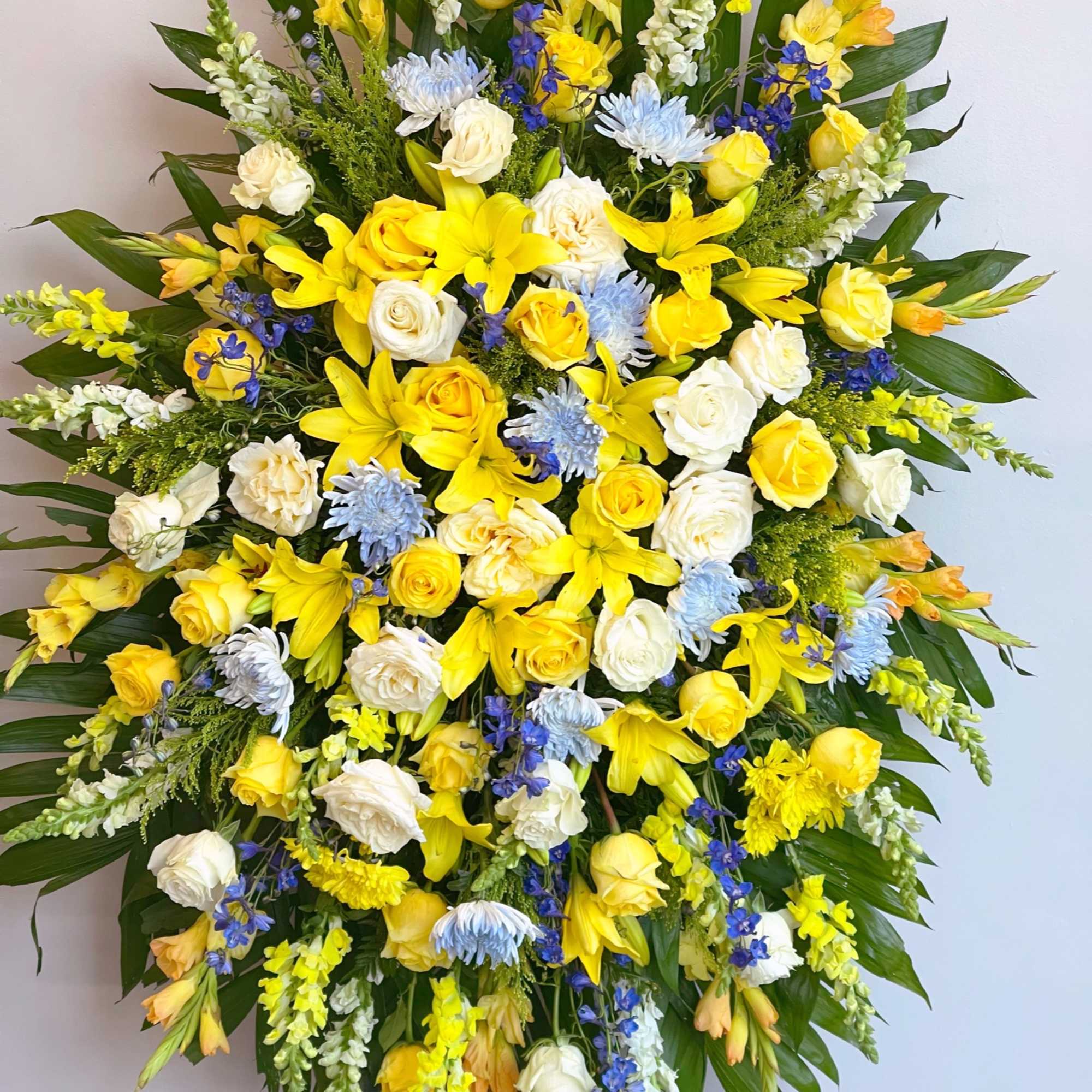 Large standing spray of yellow, white, and blue flowers